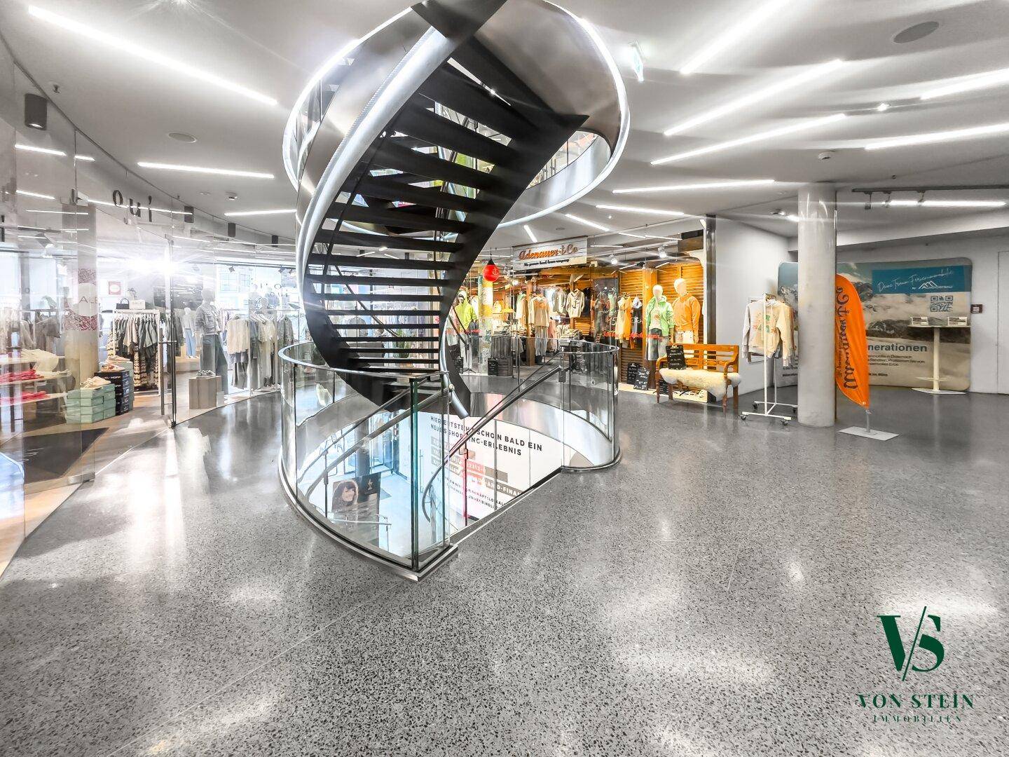 Großer, offener Gewerbebereich mit einer markanten Wendeltreppe und modernem Terrazzoboden.