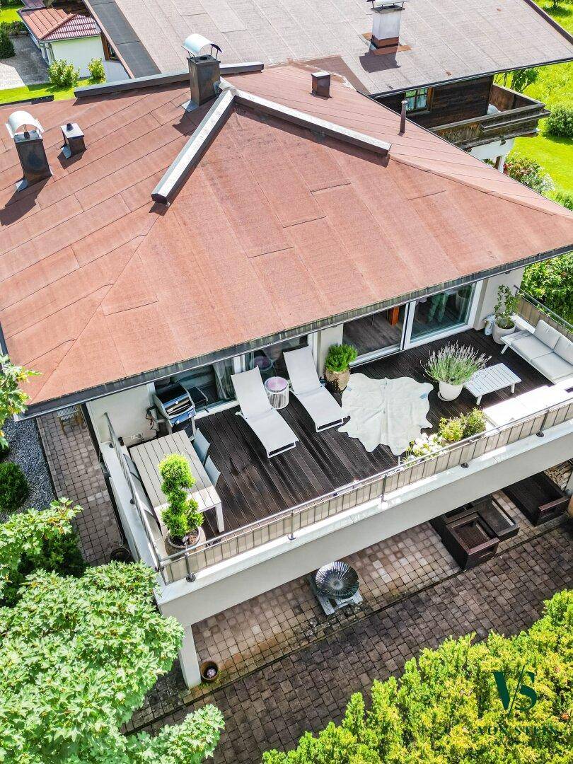 Luftaufnahme des Hauses mit großzügiger Terrasse und umliegender grüner Berglandschaft.