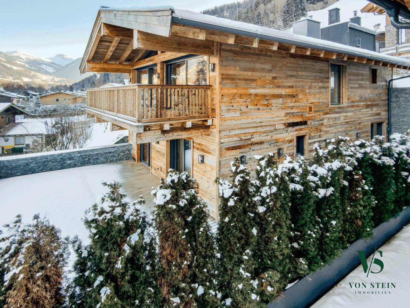 Traditionelles Holzchalet in verschneiter Berglandschaft mit Balkon und moderner Architektur.