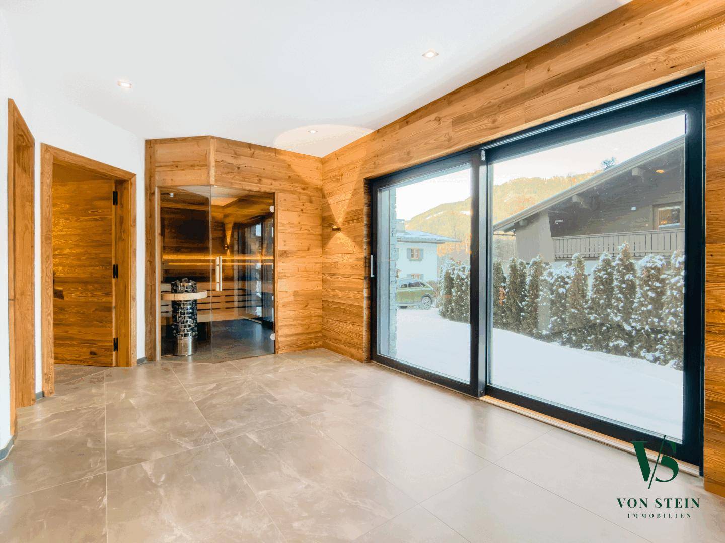 Moderner Wellnessbereich mit Sauna und großen Schiebetüren zum Außenbereich.