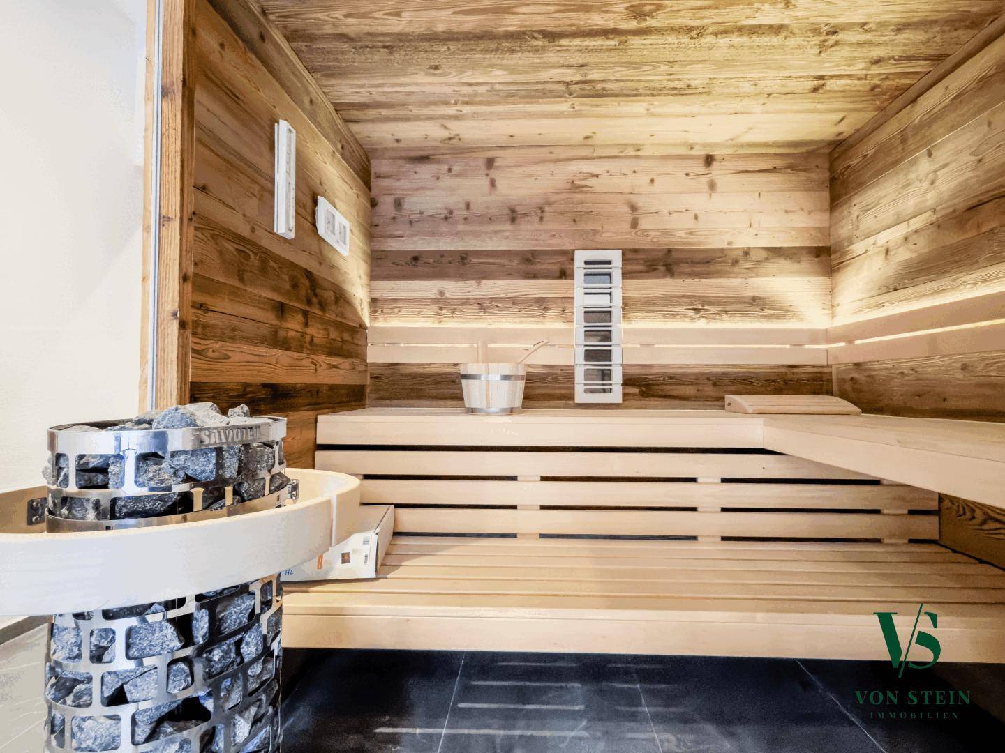Gemütliche Holzsauna mit traditionellem Ofen und bequemen Sitzbänken für Entspannung.