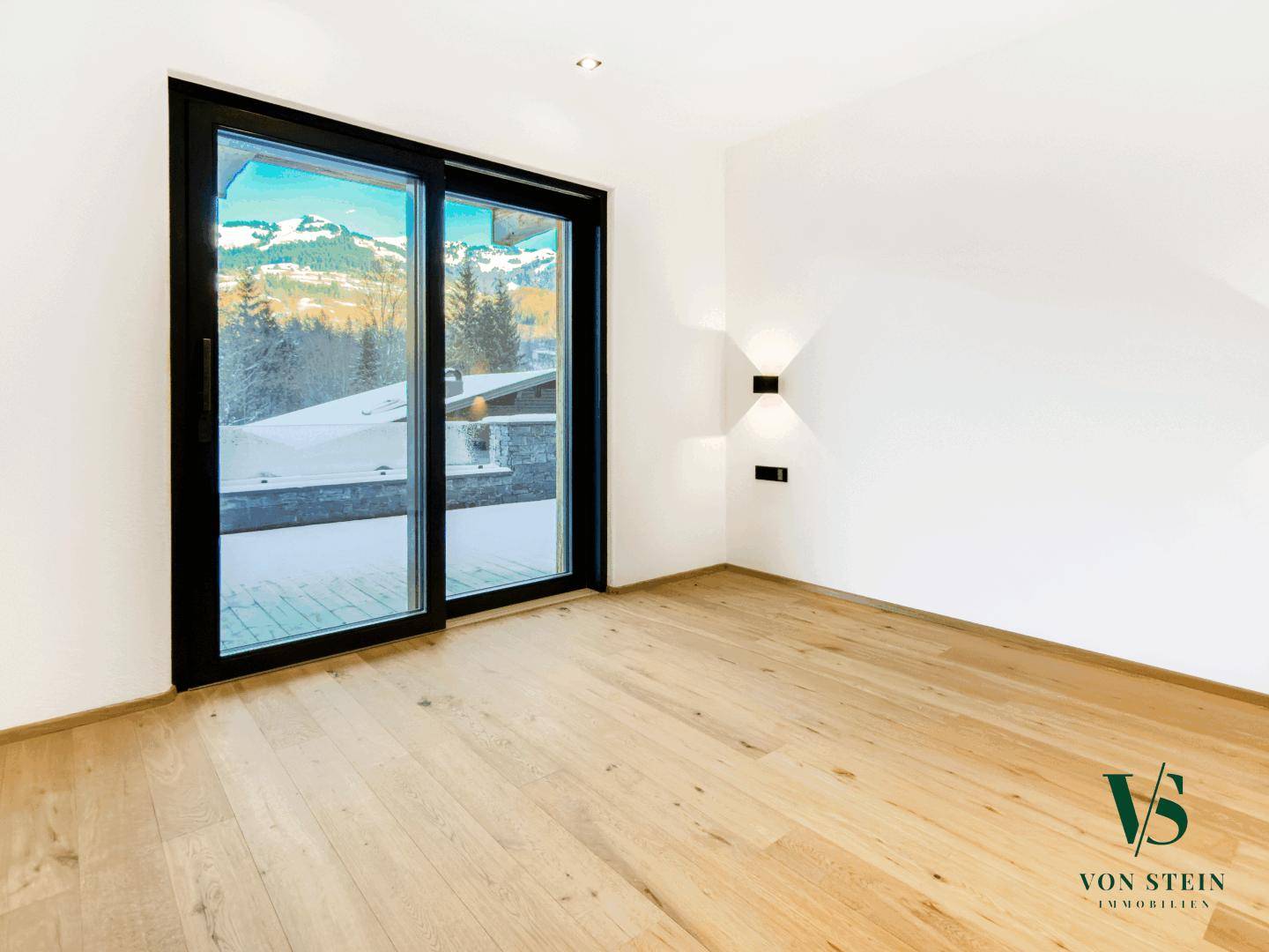 Helles Zimmer mit Holzboden, großen Fenstern und einem schönen Blick auf die Berge.