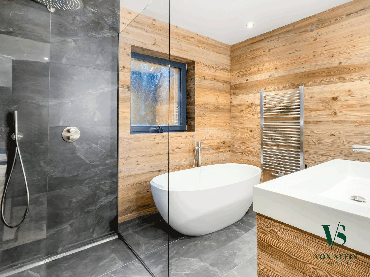 Luxuriöses Badezimmer mit freistehender Badewanne, begehbarer Dusche und Holzvertäfelung.