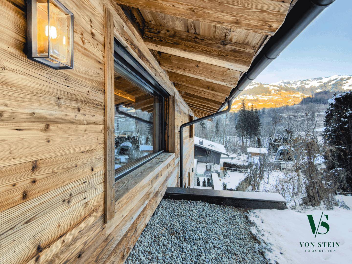 Detailansicht der Holzfassade mit modernem Fenster und Kiesbereich im Außenbereich.