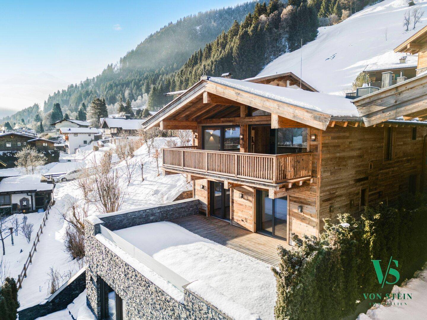 Luxuriöses Holzchalet in den verschneiten Bergen mit großer Terrasse und Balkon, ideal für Winterurlaub.