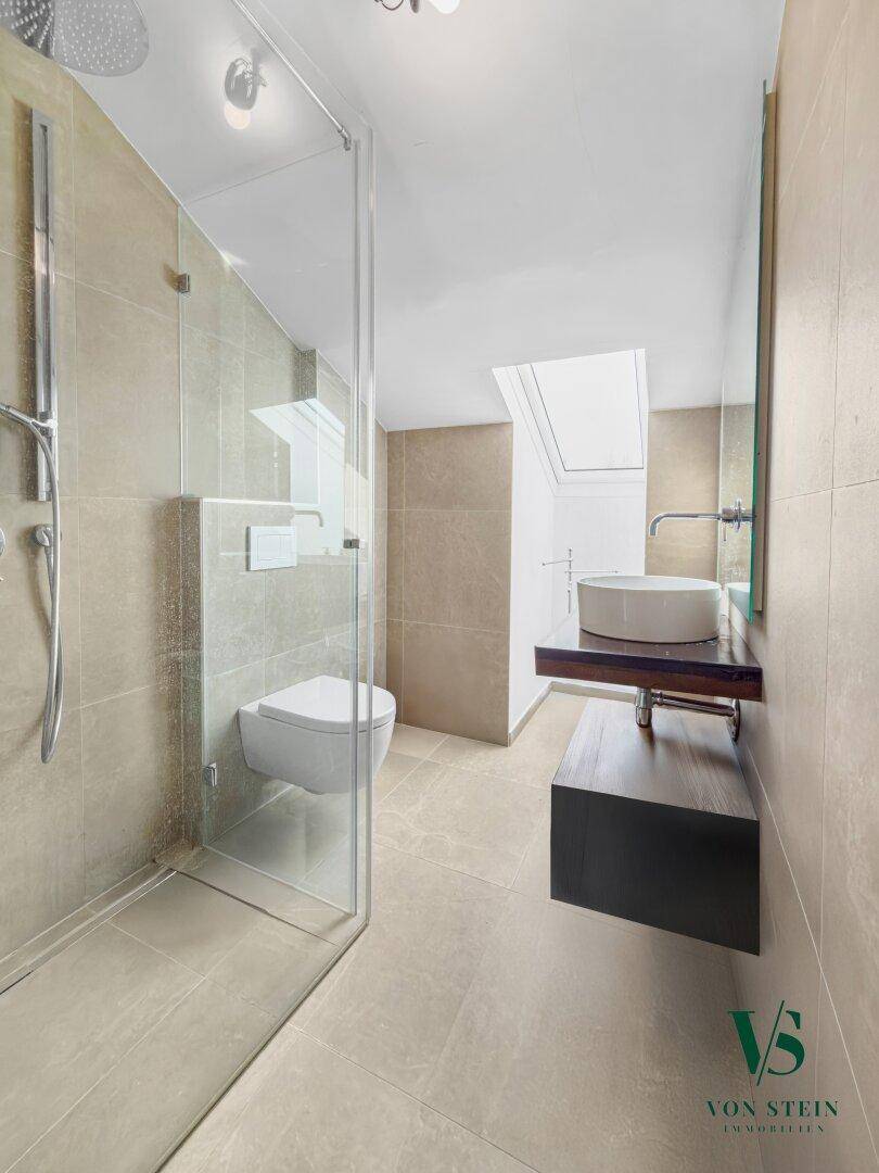 Modernes Dachbad mit begehbarer Dusche, wandhängendem WC, Waschbecken und Dachfenster.