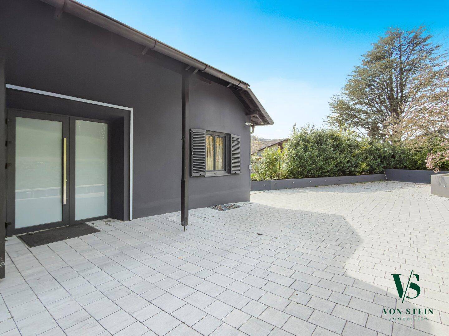 Eingangsbereich des Hauses mit gepflastertem Vorplatz und moderner Fassade.