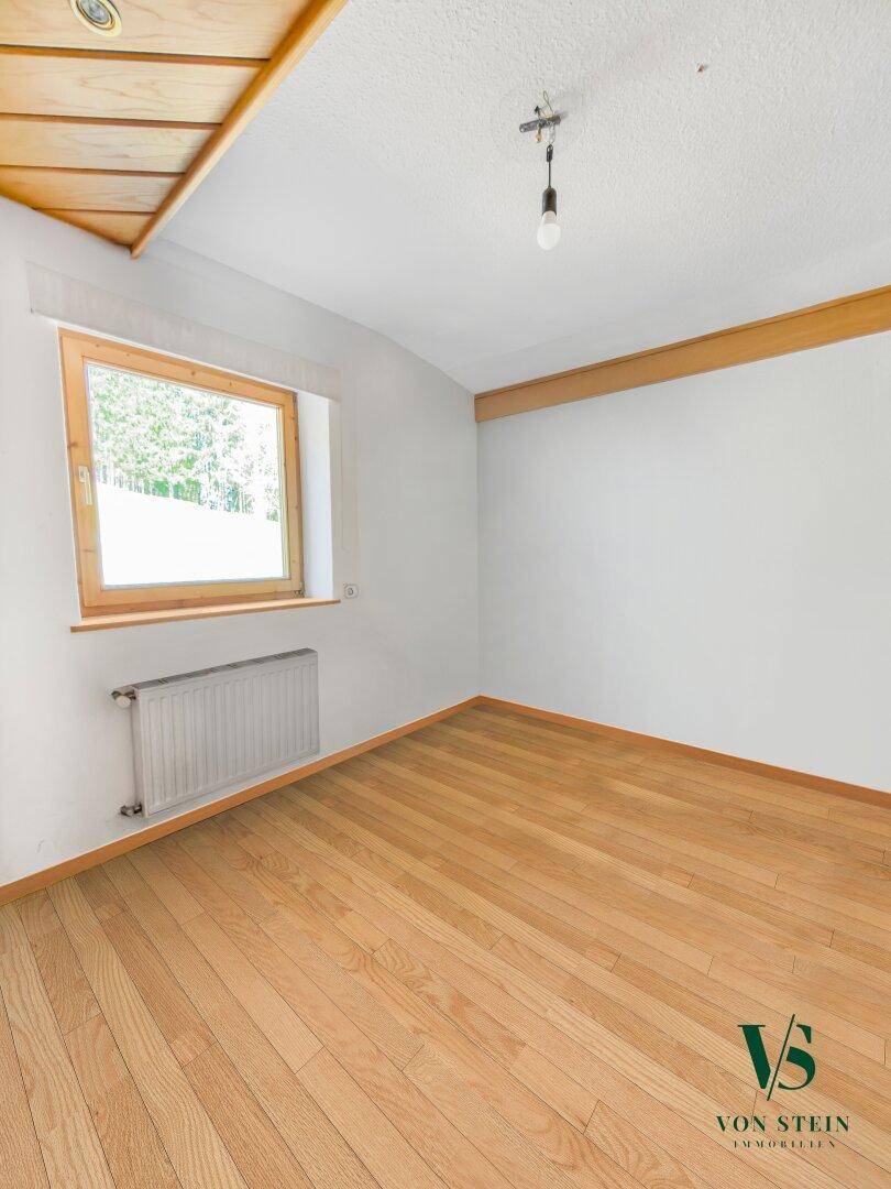 Ruhiges Schlafzimmer mit Parkettboden, einem Fenster und einfacher Deckenbeleuchtung.