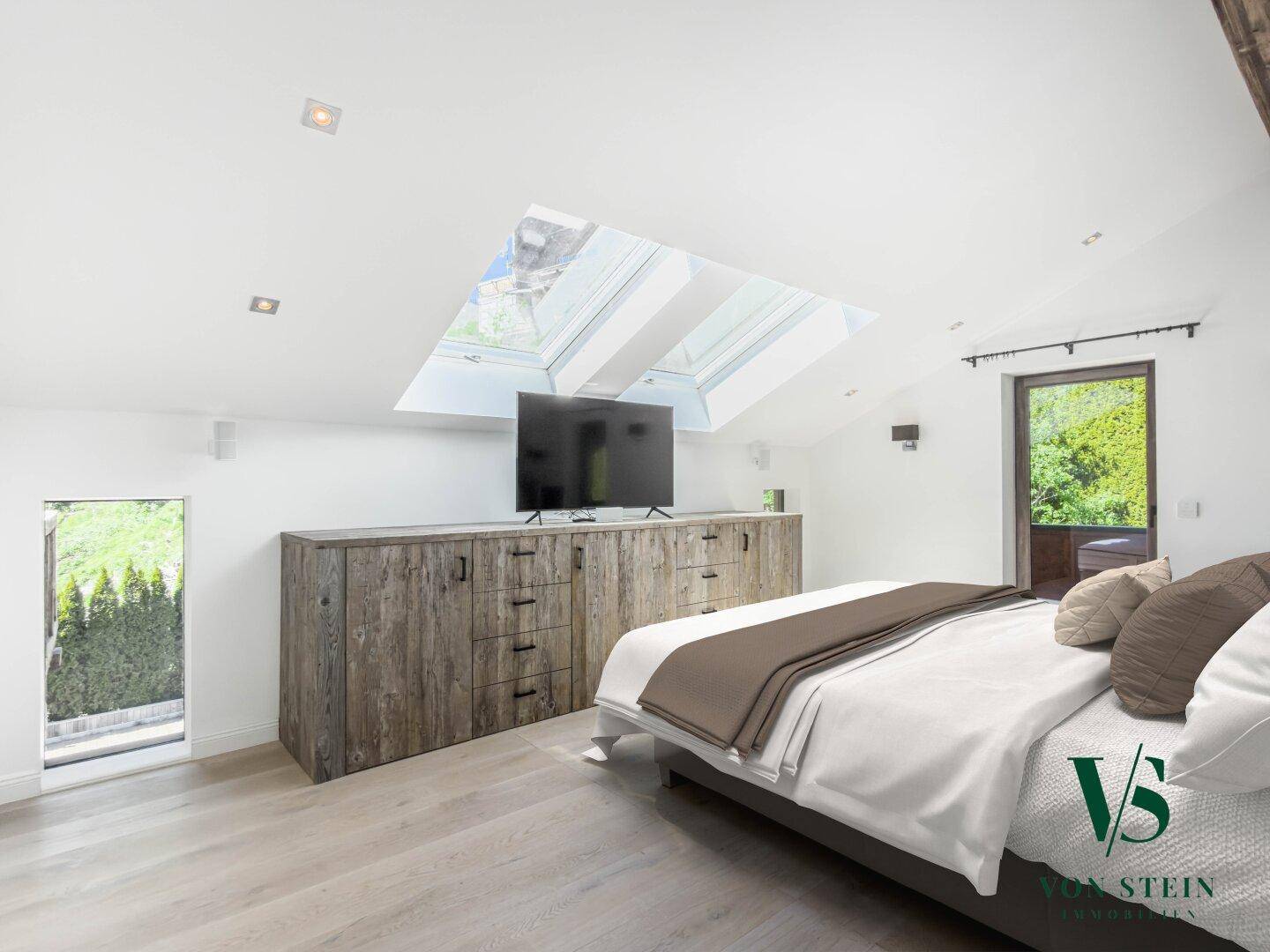 Helles Schlafzimmer im Dachgeschoss mit Dachfenstern, Holzboden und integriertem Schrank.
