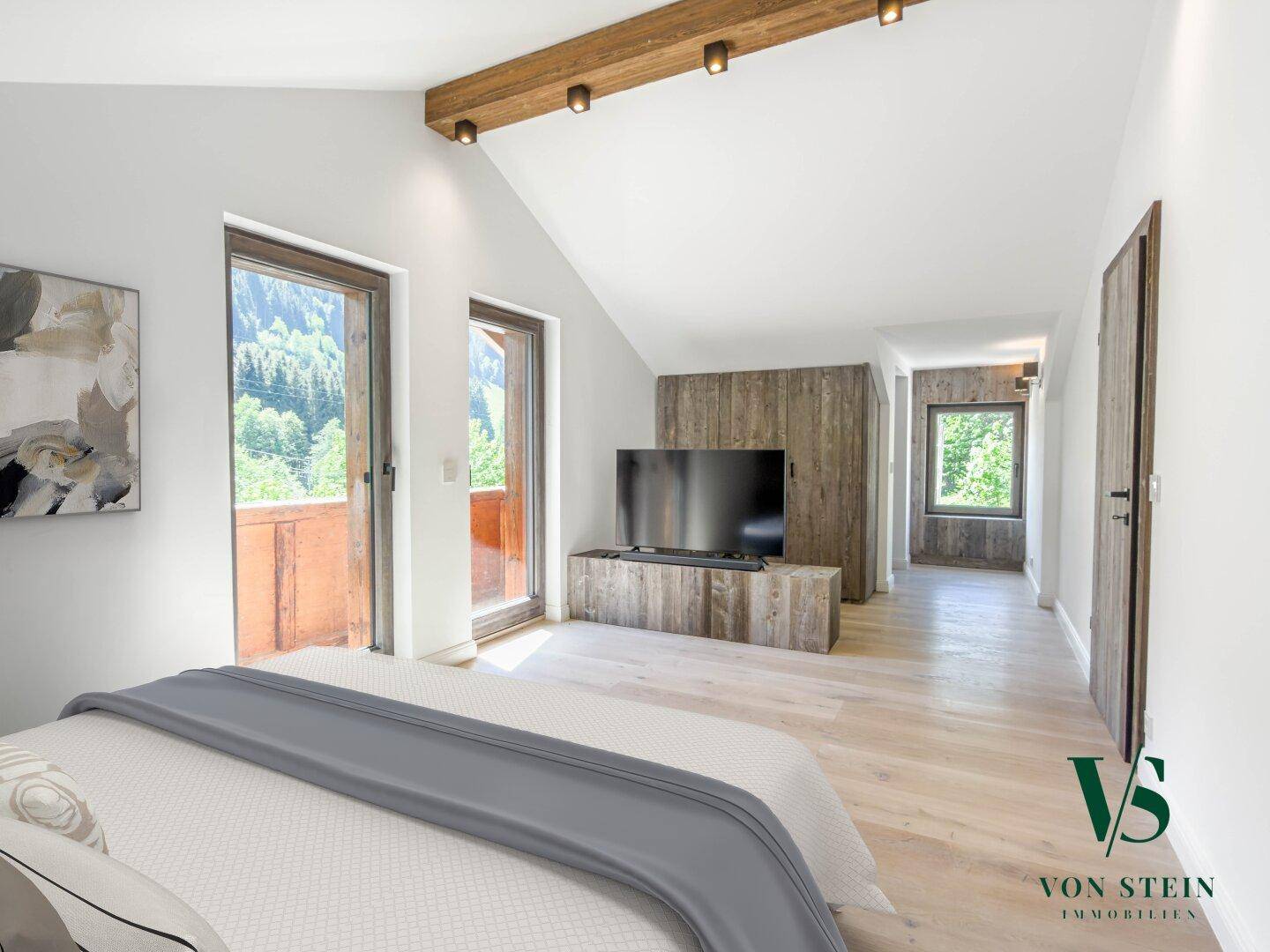 Helles Schlafzimmer mit Holzbalken, Zugang zum Balkon und Blick ins Grüne.