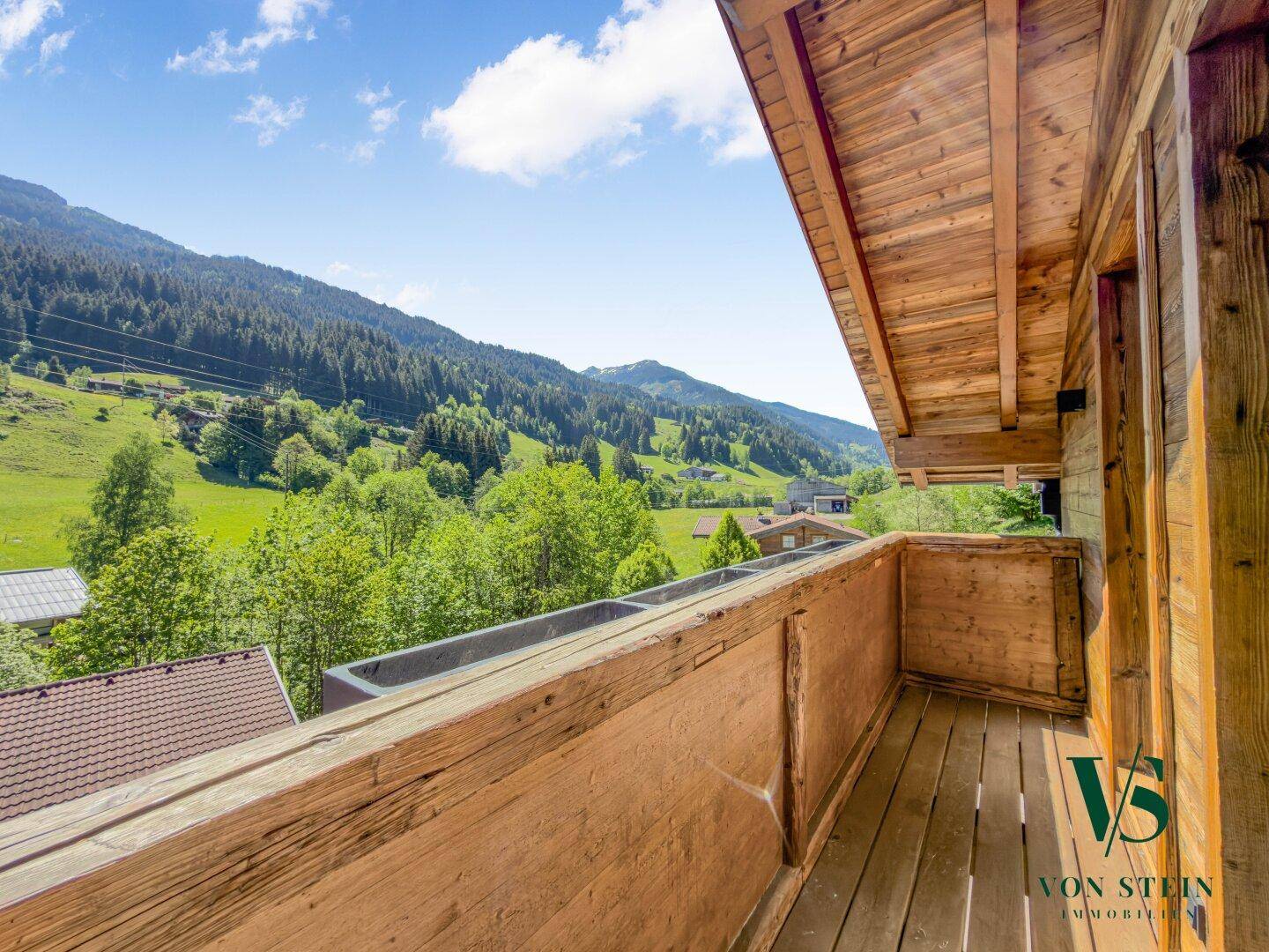 Geräumiger Holzbalkon mit rustikalem Charme und atemberaubendem Blick auf die Alpen.