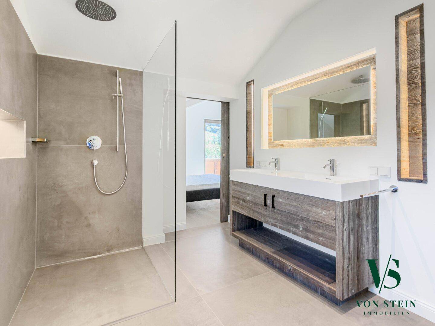 Modernes Badezimmer mit großer begehbarer Dusche und Doppelwaschbecken mit Holzunterschrank.