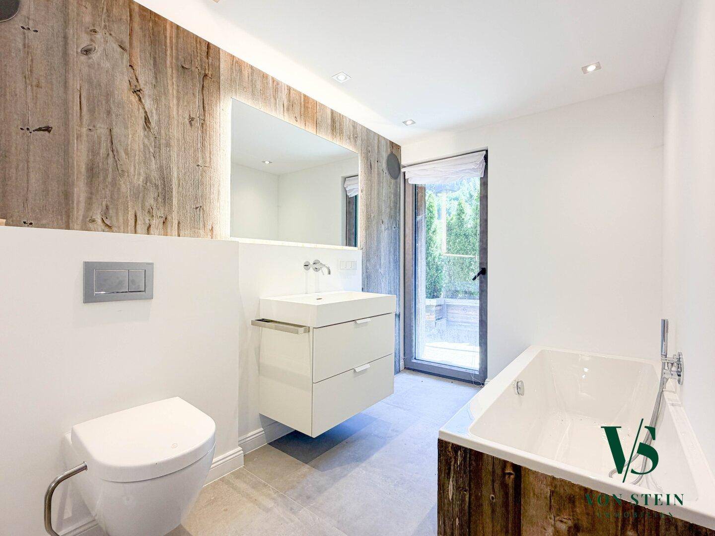Modernes Badezimmer mit Badewanne, schwebendem Waschtisch und Holzakzenten.
