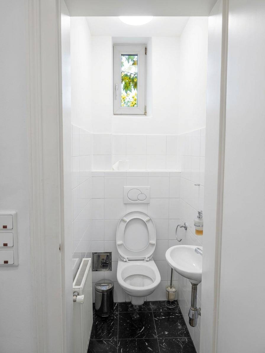 Kleines Gäste-WC mit Fenster, weißen Fliesen und wandhängendem WC.