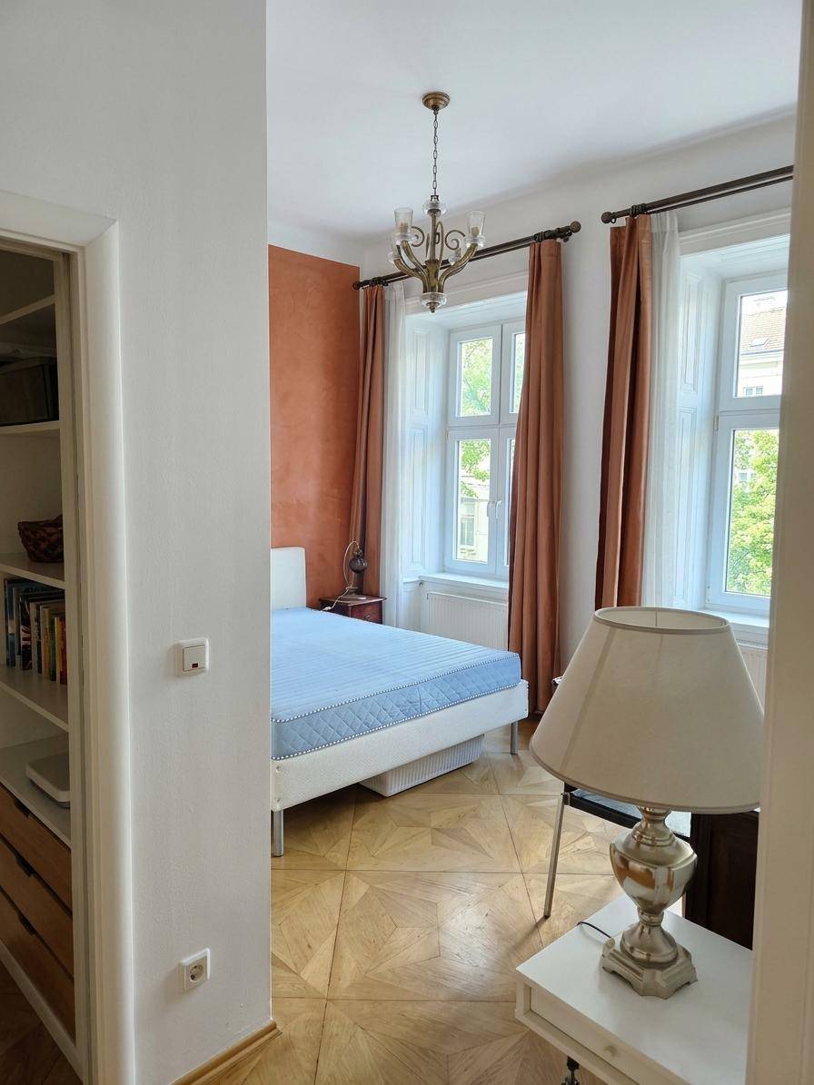 Schlafzimmer mit Parkettboden, Doppelbett und Fenster mit Blick ins Grüne.