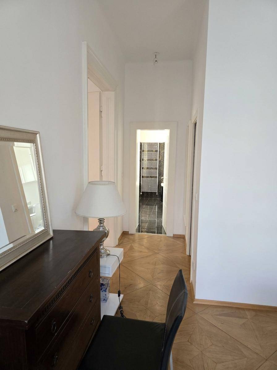 Heller Flur mit Parkettboden, der zu weiteren Räumen und dem Badezimmer führt.