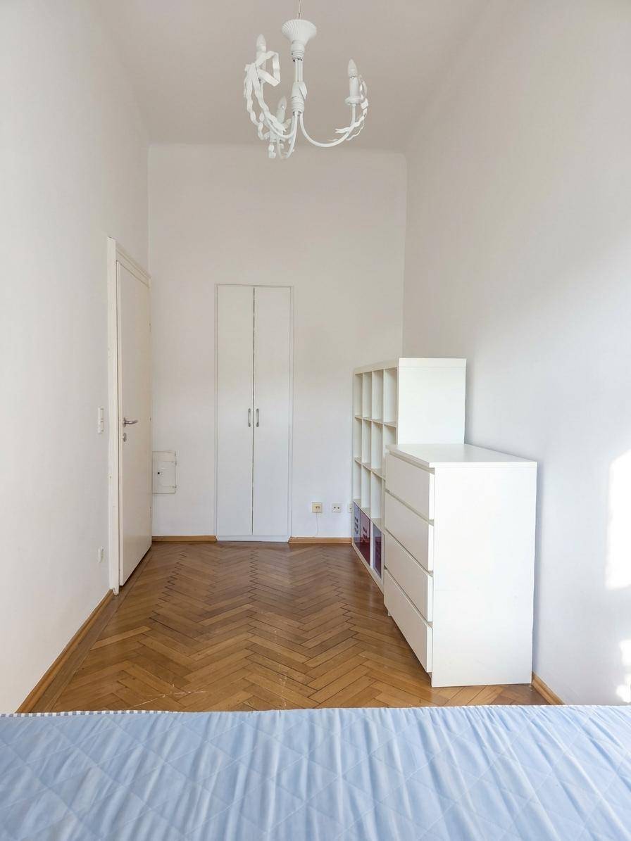 Geräumiges Schlafzimmer mit Parkettboden, weißem Kleiderschrank und Kommode.