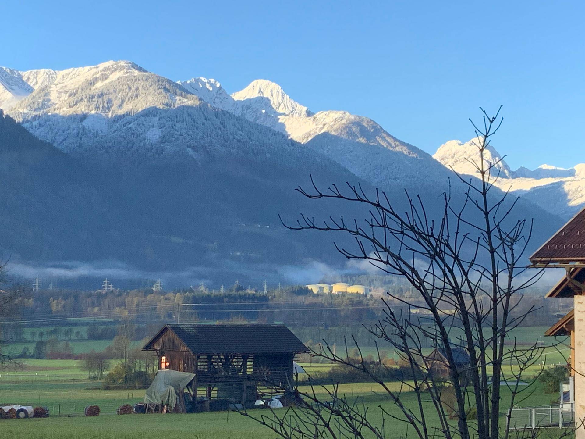 Malerischer Blick auf schneebedeckte Berge und eine ländliche Landschaft mit einem traditionellen Holzschuppen.