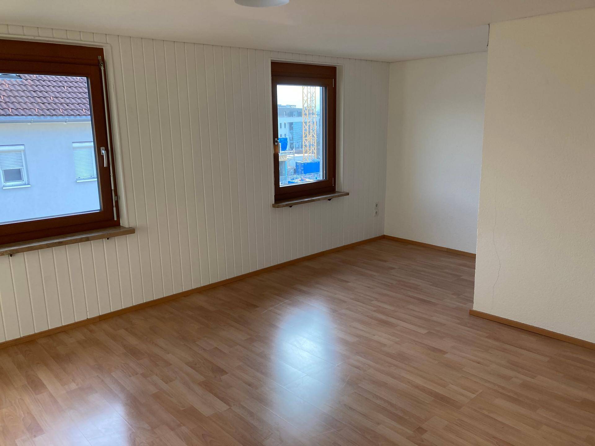 Heller Raum mit Laminatboden und vertäfelten Wänden, bietet eine gemütliche Atmosphäre.