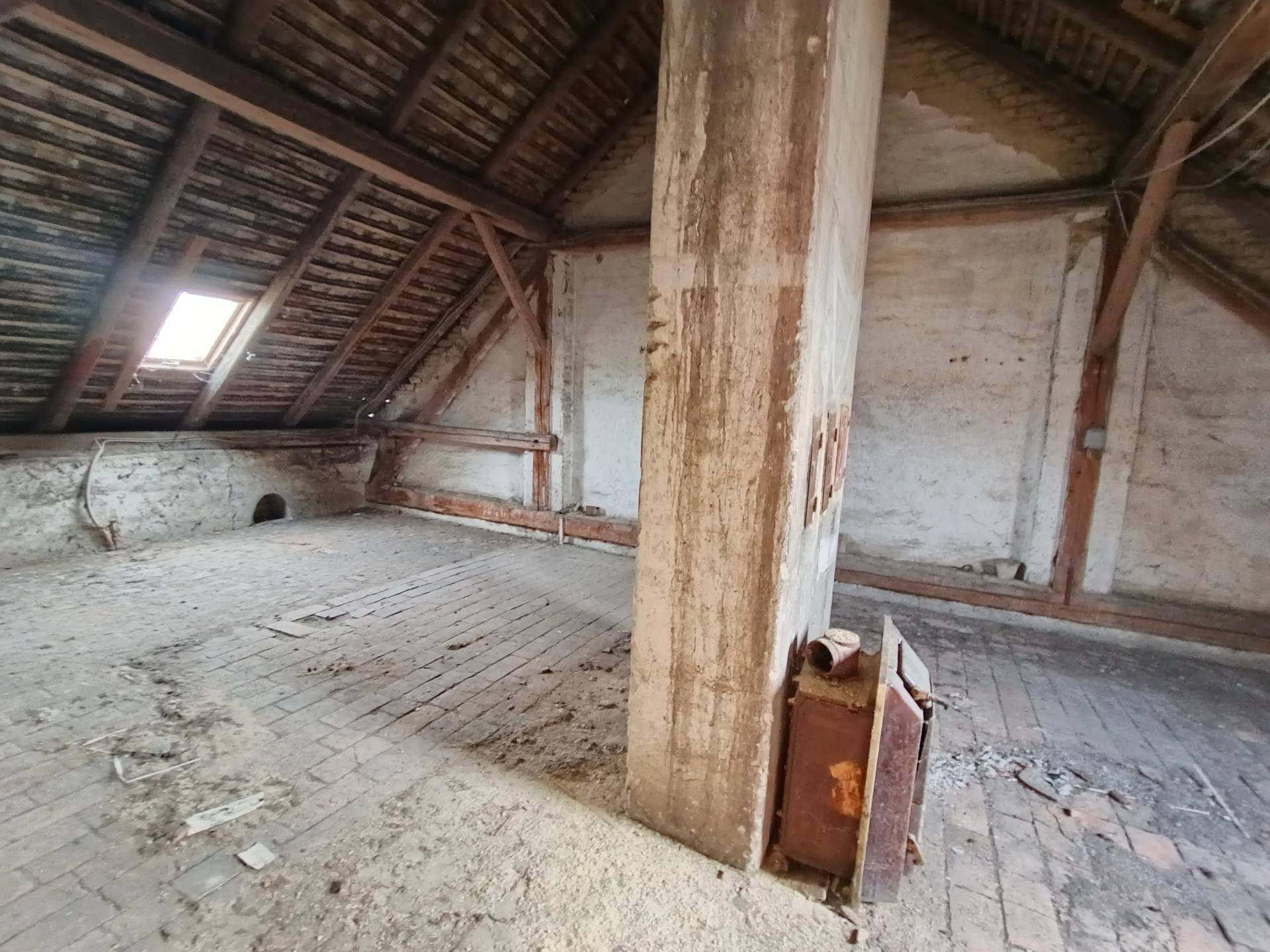 Geräumiger Dachboden mit sichtbarer Holzkonstruktion und einem Dachfenster für Tageslicht.