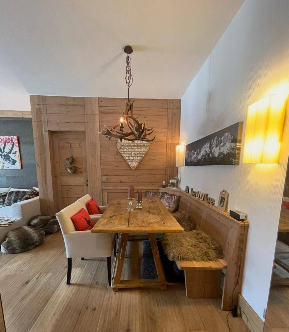 Rustikaler Essbereich mit Holztisch, eingebauter Sitzbank und Hirschgeweih-Kronleuchter.