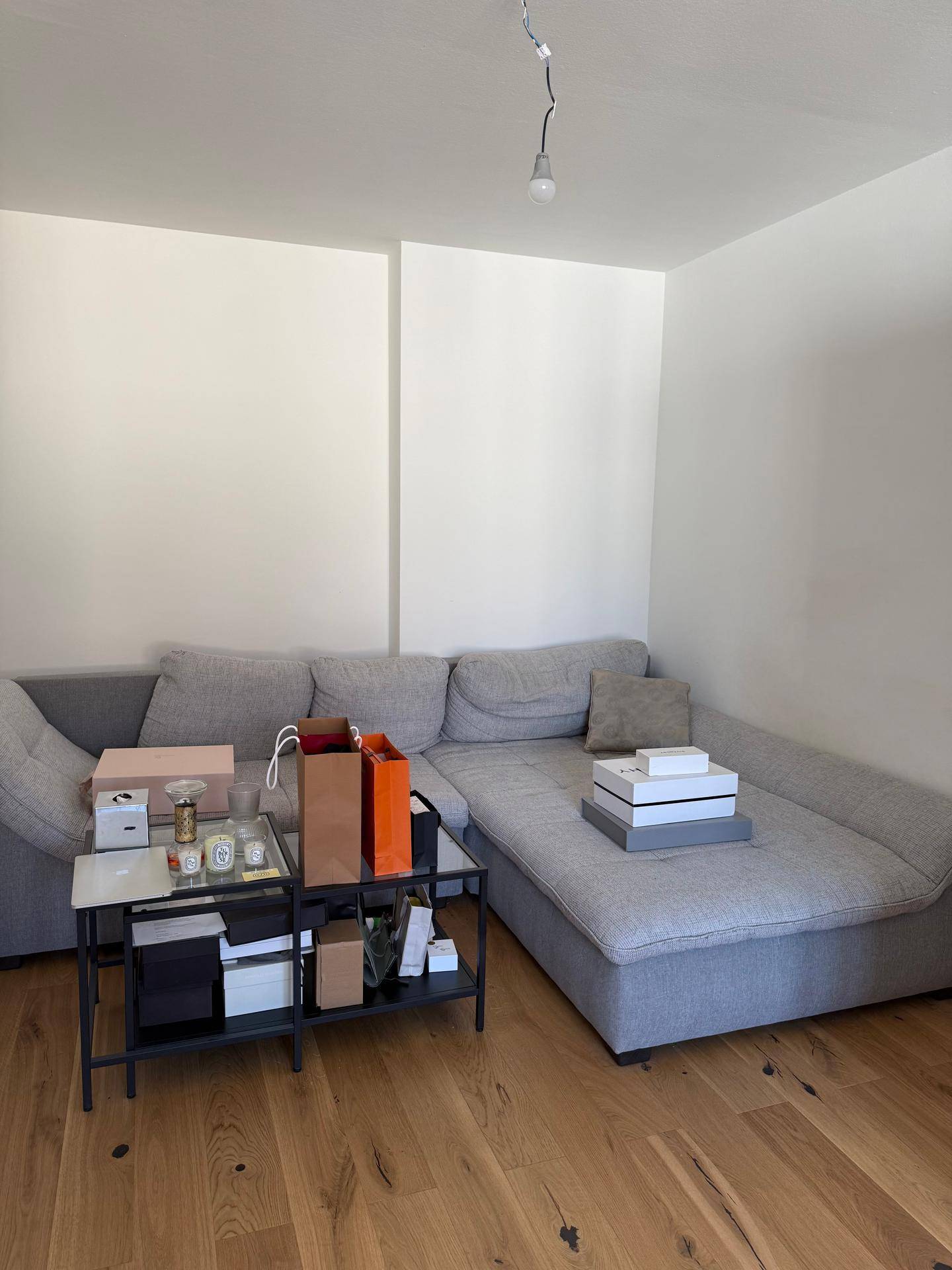 Gemütliches Wohnzimmer mit einem großen grauen Ecksofa und hellem Holzfußboden.