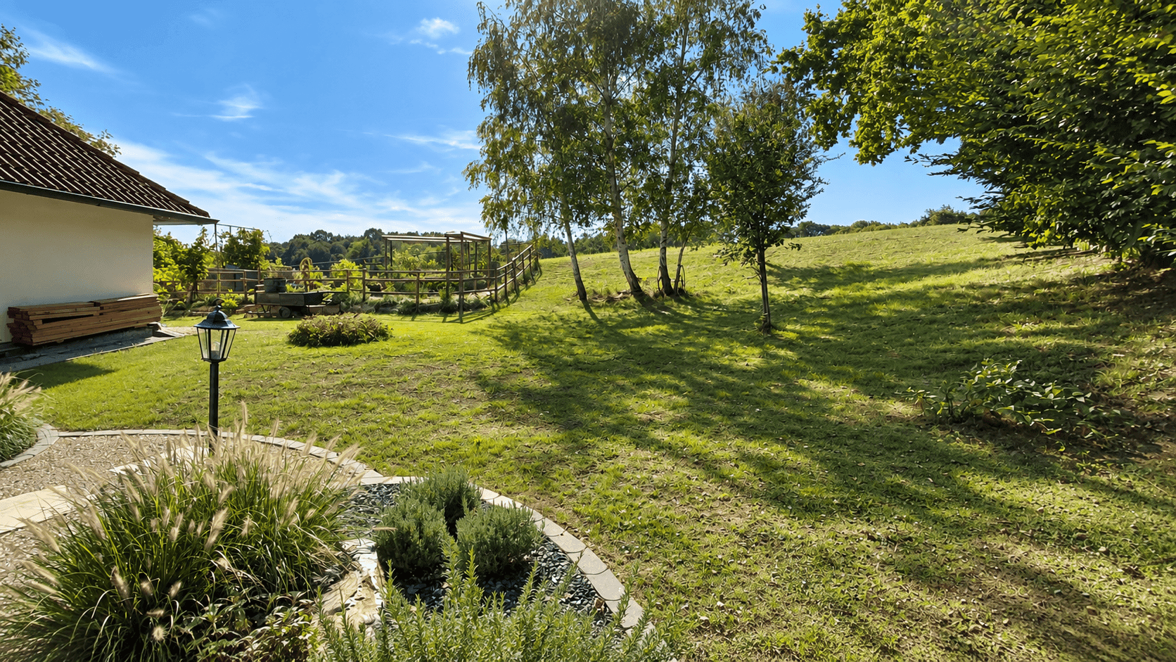 Weitläufiger Gartenbereich mit gepflegtem Rasen, Bäumen und einem malerischen Blick auf die umliegende Landschaft.