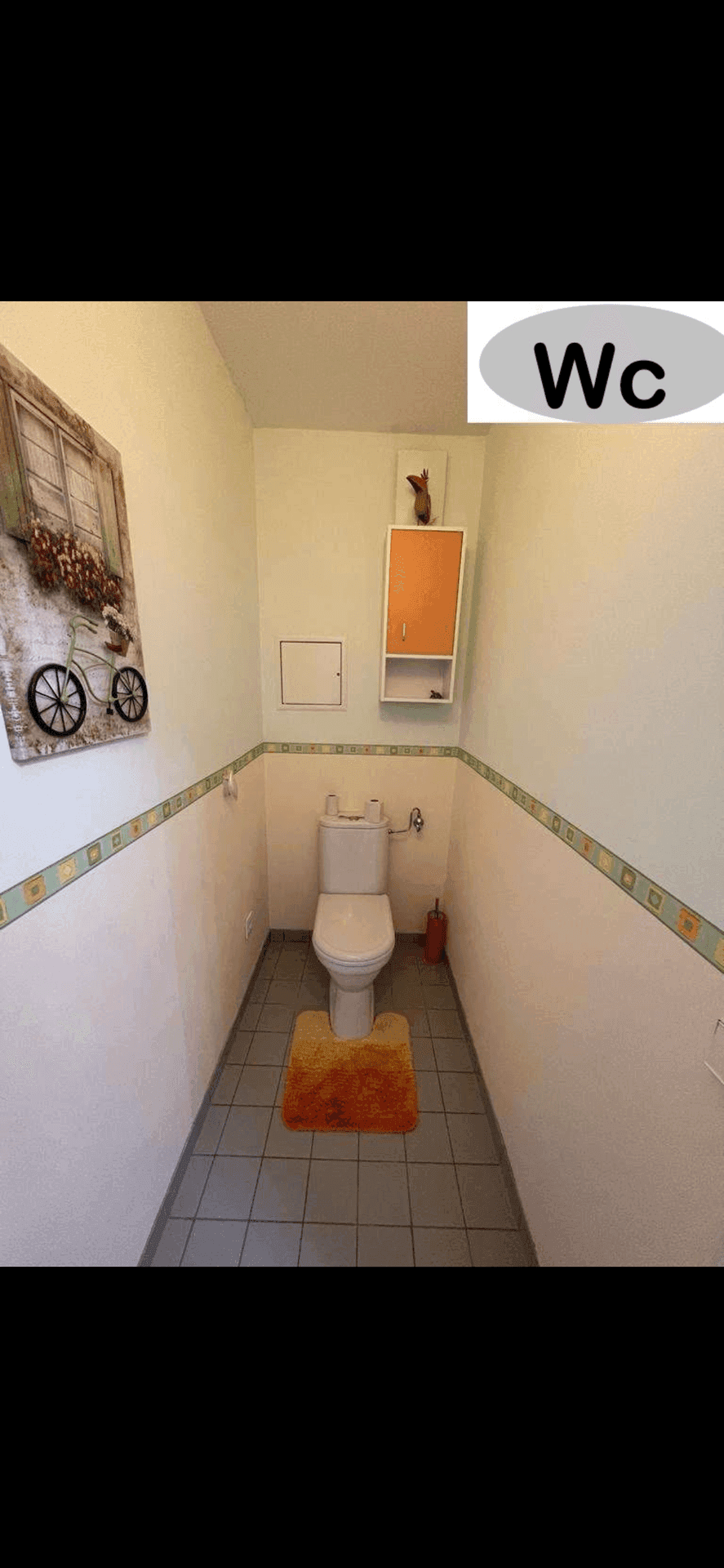 Kleines Gäste-WC mit Toilette und Wandregal, dekoriert mit einem Fahrradbild.