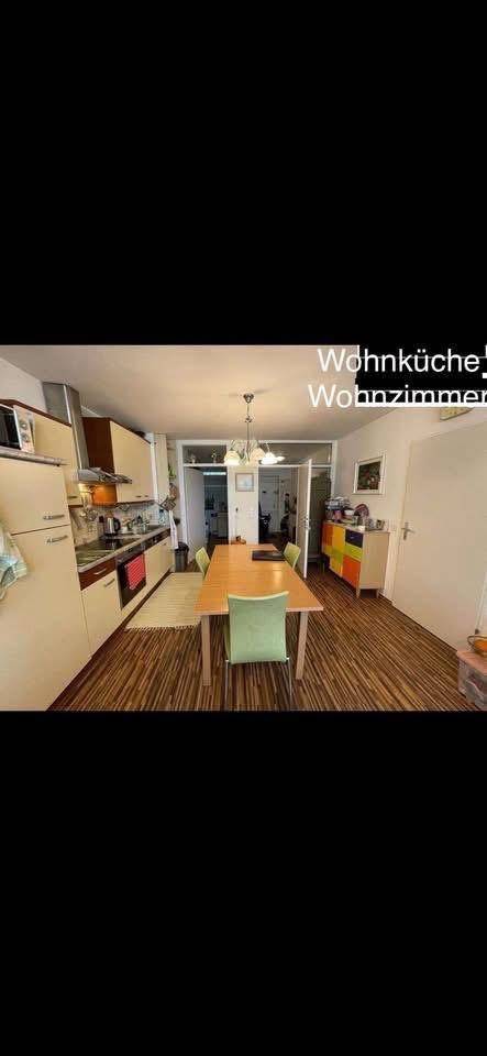 Wohnküche mit Esstisch und Zugang zum Wohnzimmer, ausgestattet mit Holzoptikboden.