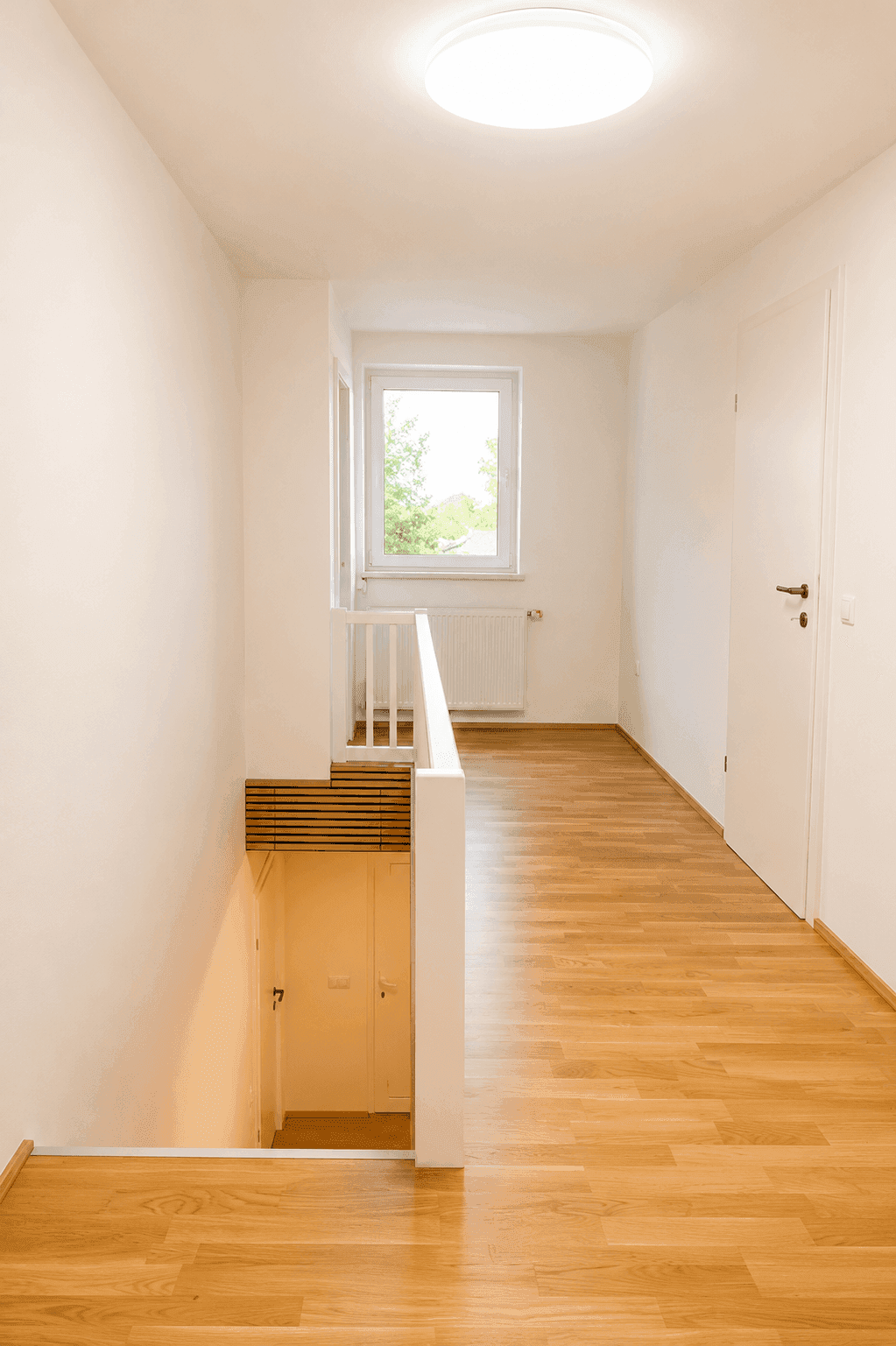 Heller Flur im Obergeschoss mit Parkettboden, Fenster und Zugang zu weiteren Zimmern.