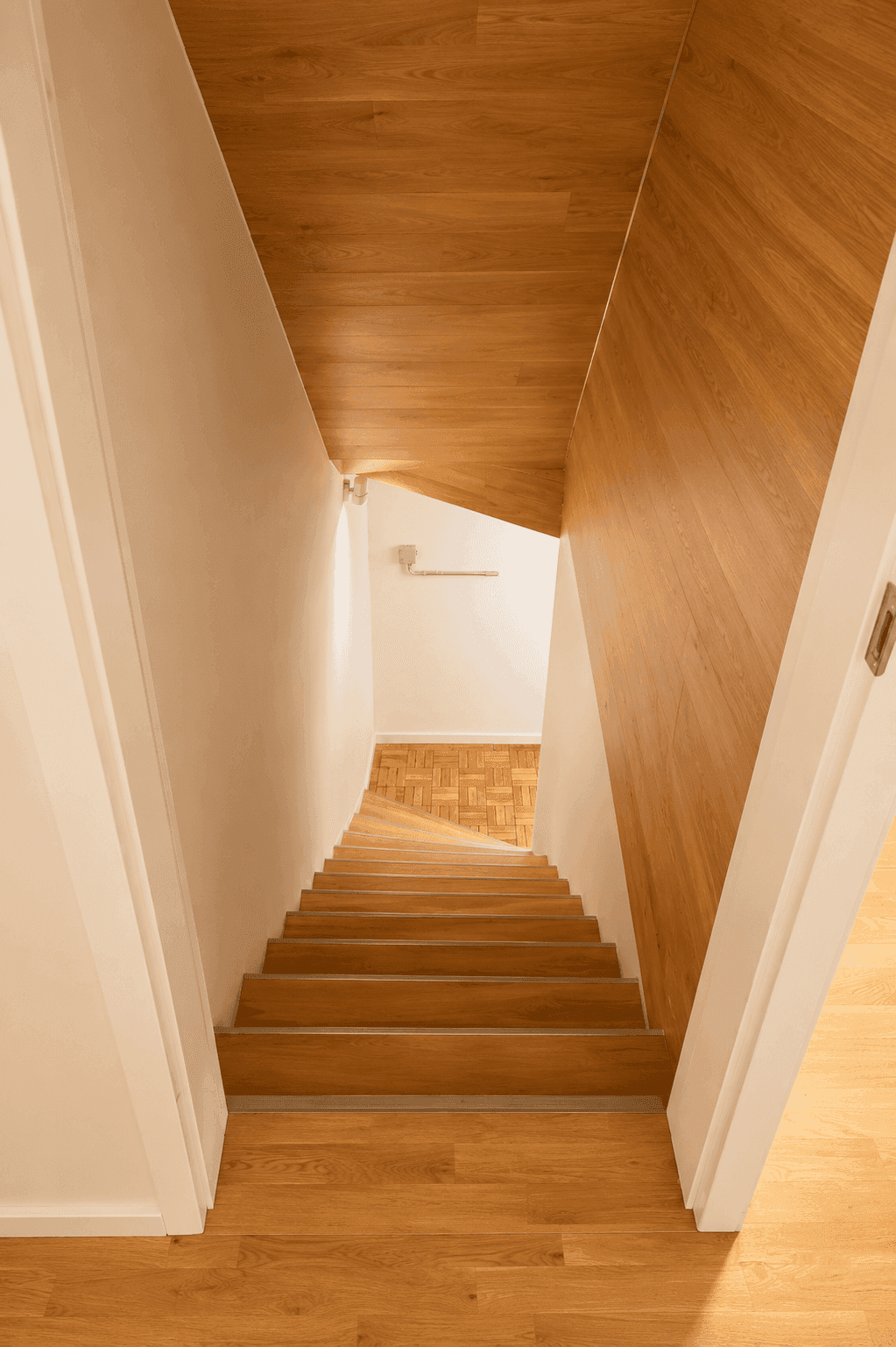 Treppenhaus mit Holzstufen und Holzverkleidung, das in das untere Stockwerk führt.