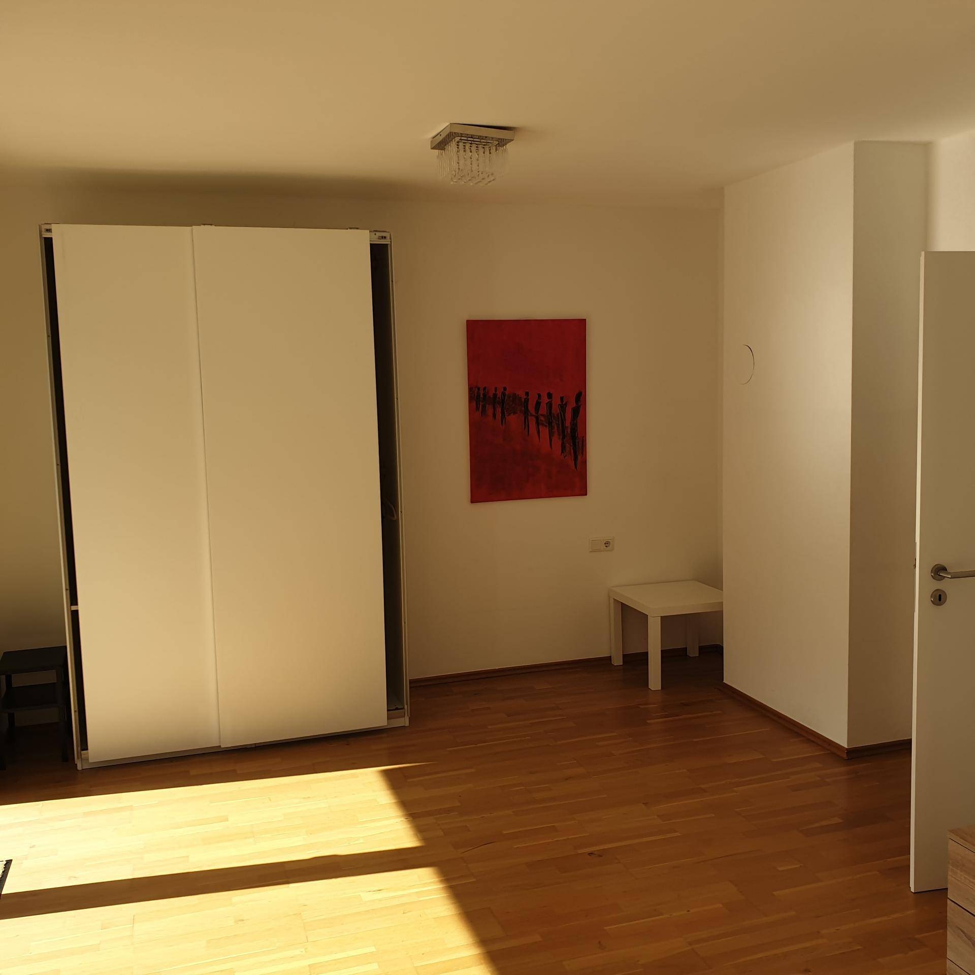 Geräumiges Zimmer mit Holzboden und großem Kleiderschrank, vielseitig nutzbar.