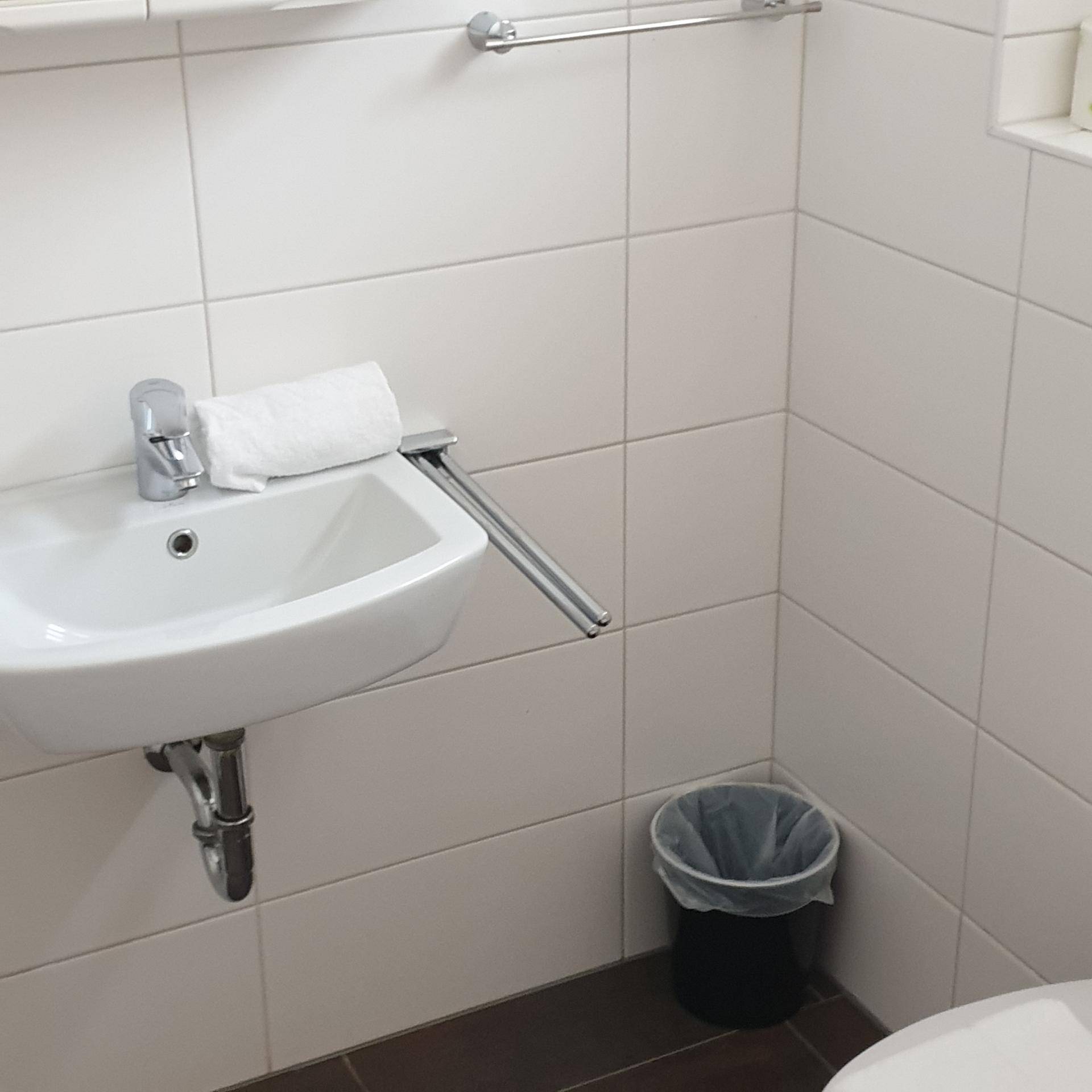 Kleines Gäste-WC mit Waschbecken und weißen Fliesen, praktisch und funktional.