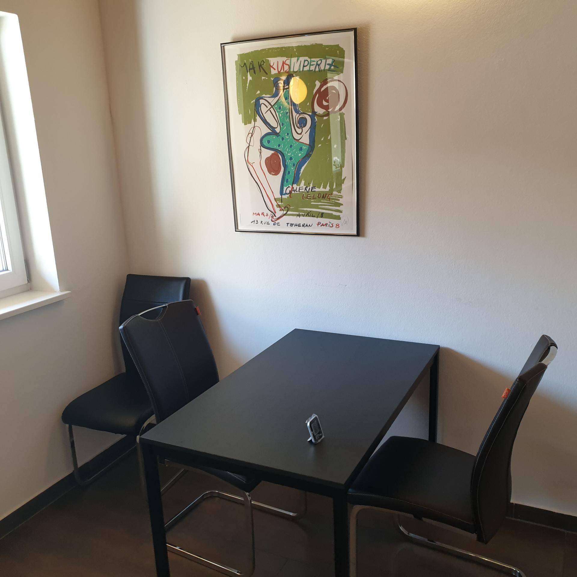 Kleiner Essbereich mit schwarzem Tisch und Stühlen, ideal für schnelle Mahlzeiten.