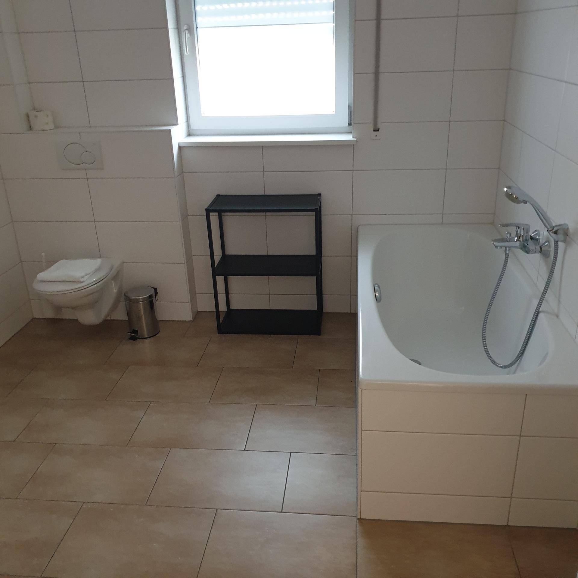 Geräumiges Badezimmer mit Badewanne, Toilette und Fenster für Tageslicht.