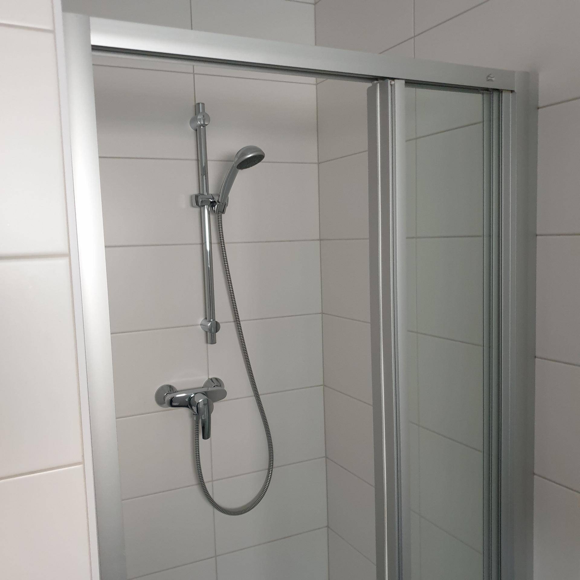Duschkabine mit Glaswand und moderner Armatur in einem gefliesten Badezimmer.