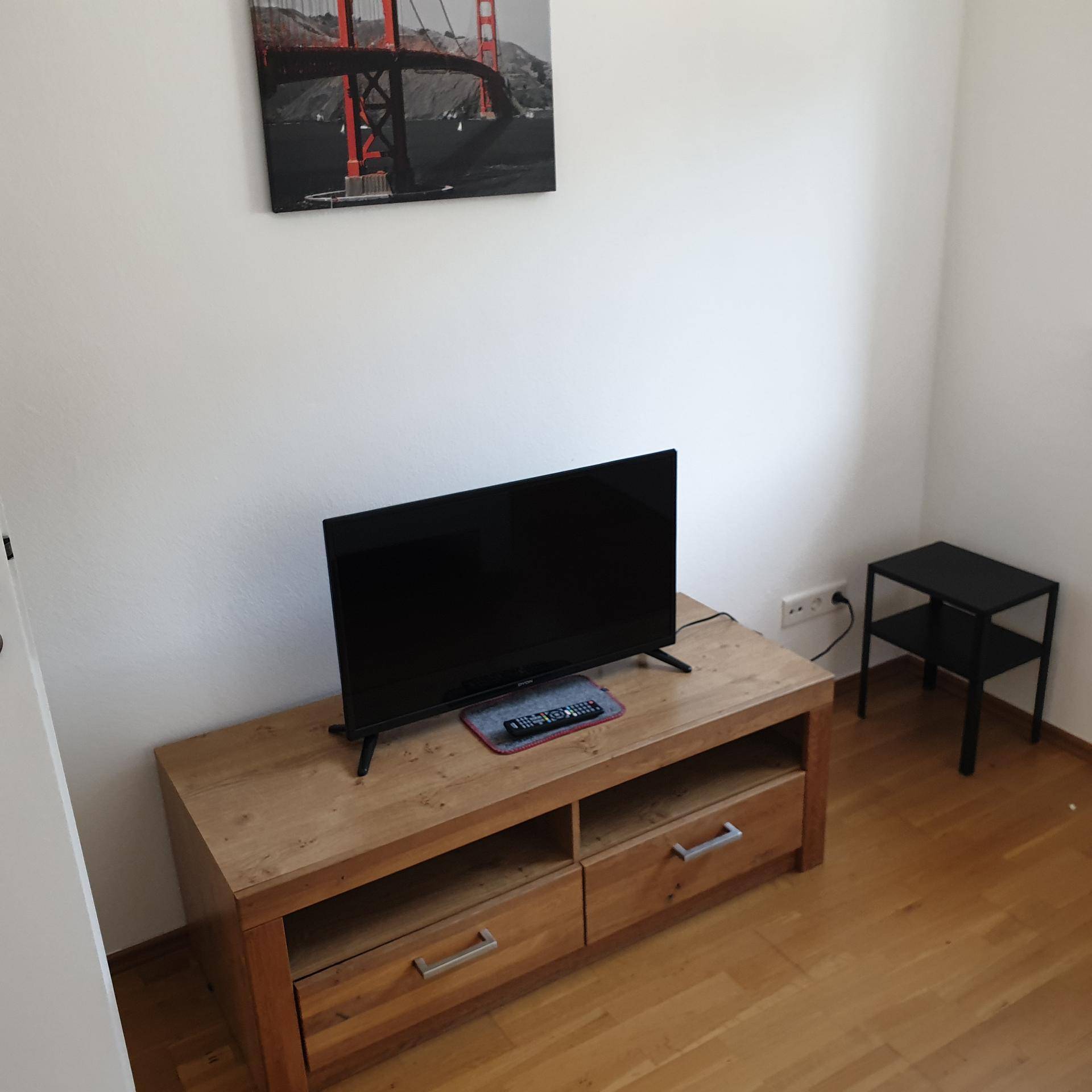 Schlafzimmer mit Fernseher und Holzboden, ideal für entspannte Abende.