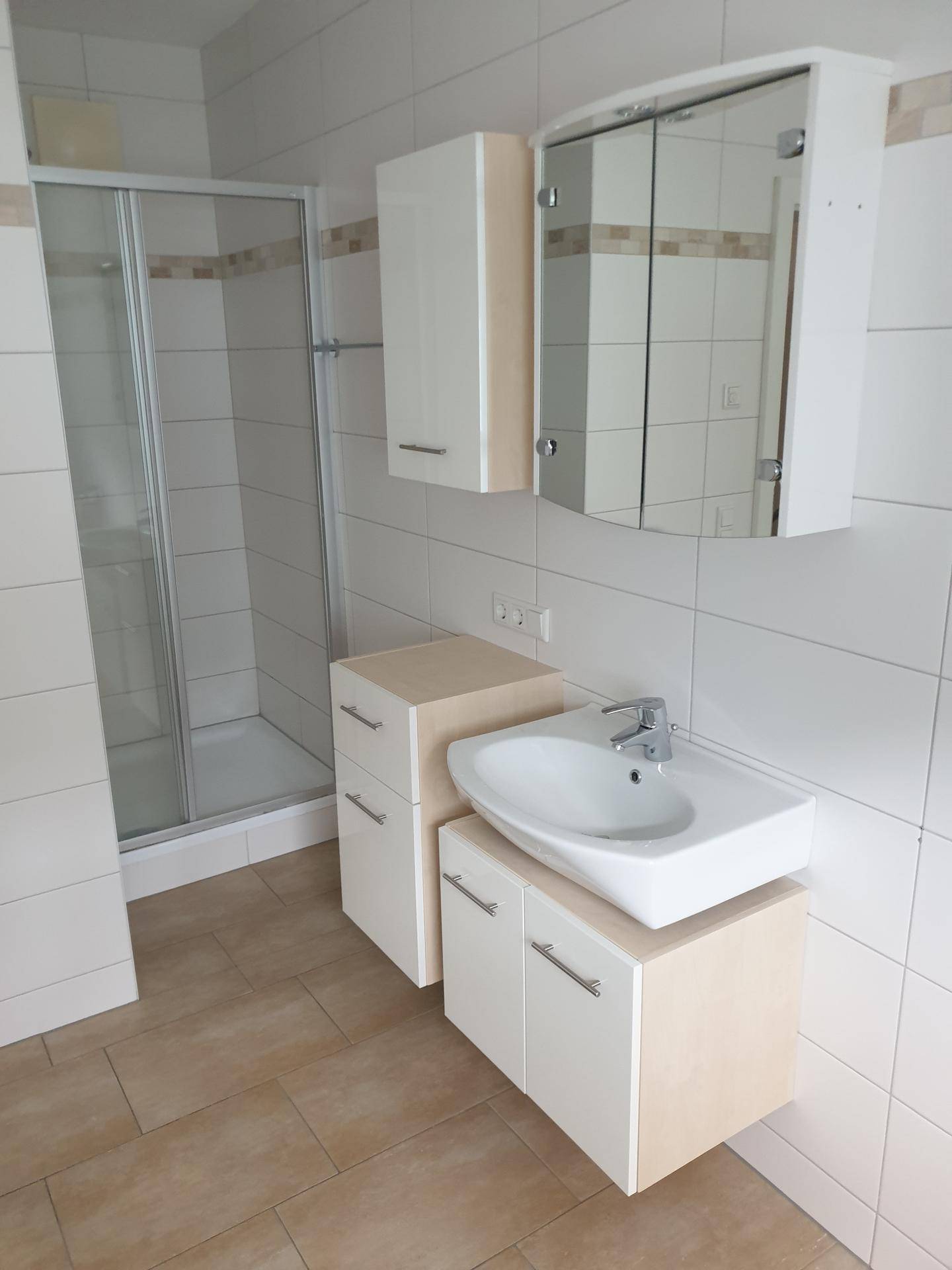 Modernes Badezimmer mit Duschkabine, Waschbecken und Spiegelschrank.