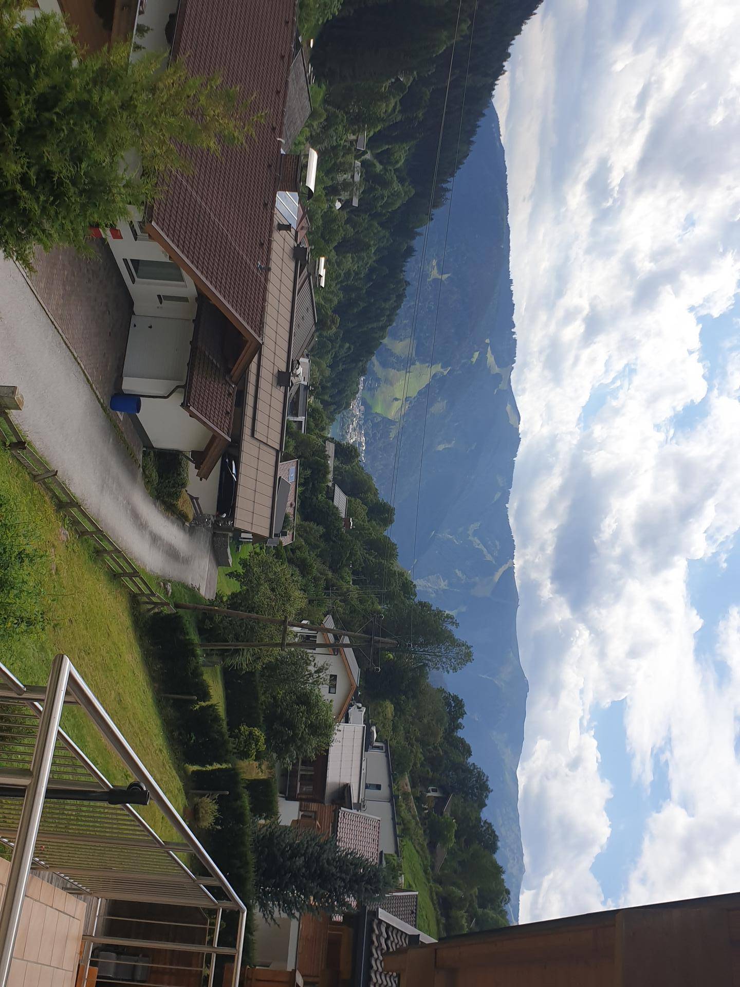 Panoramablick auf die Berge und umliegende Häuser von einem Balkon aus.