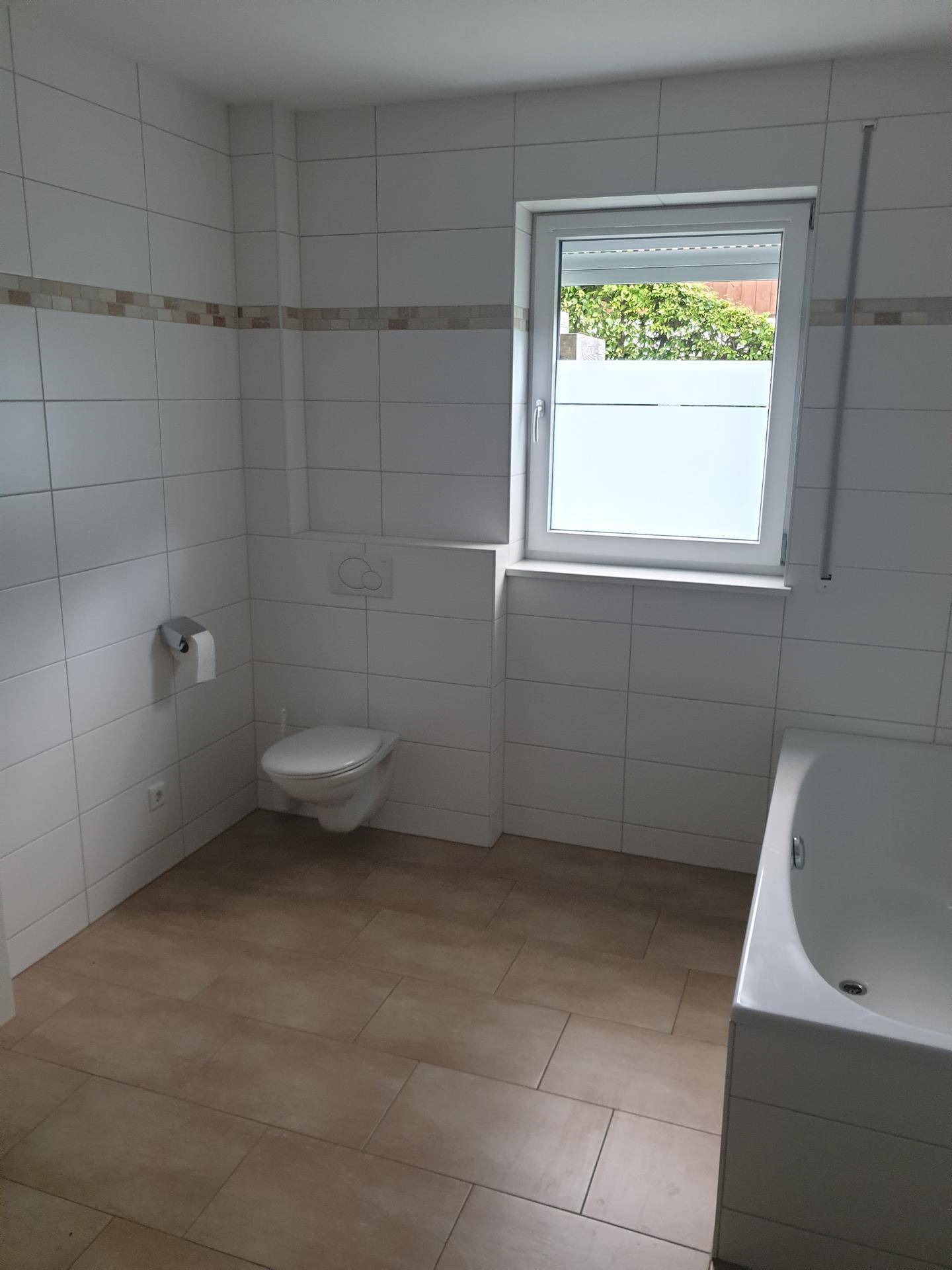 Badezimmer mit Toilette, Fenster und einer Badewanne.