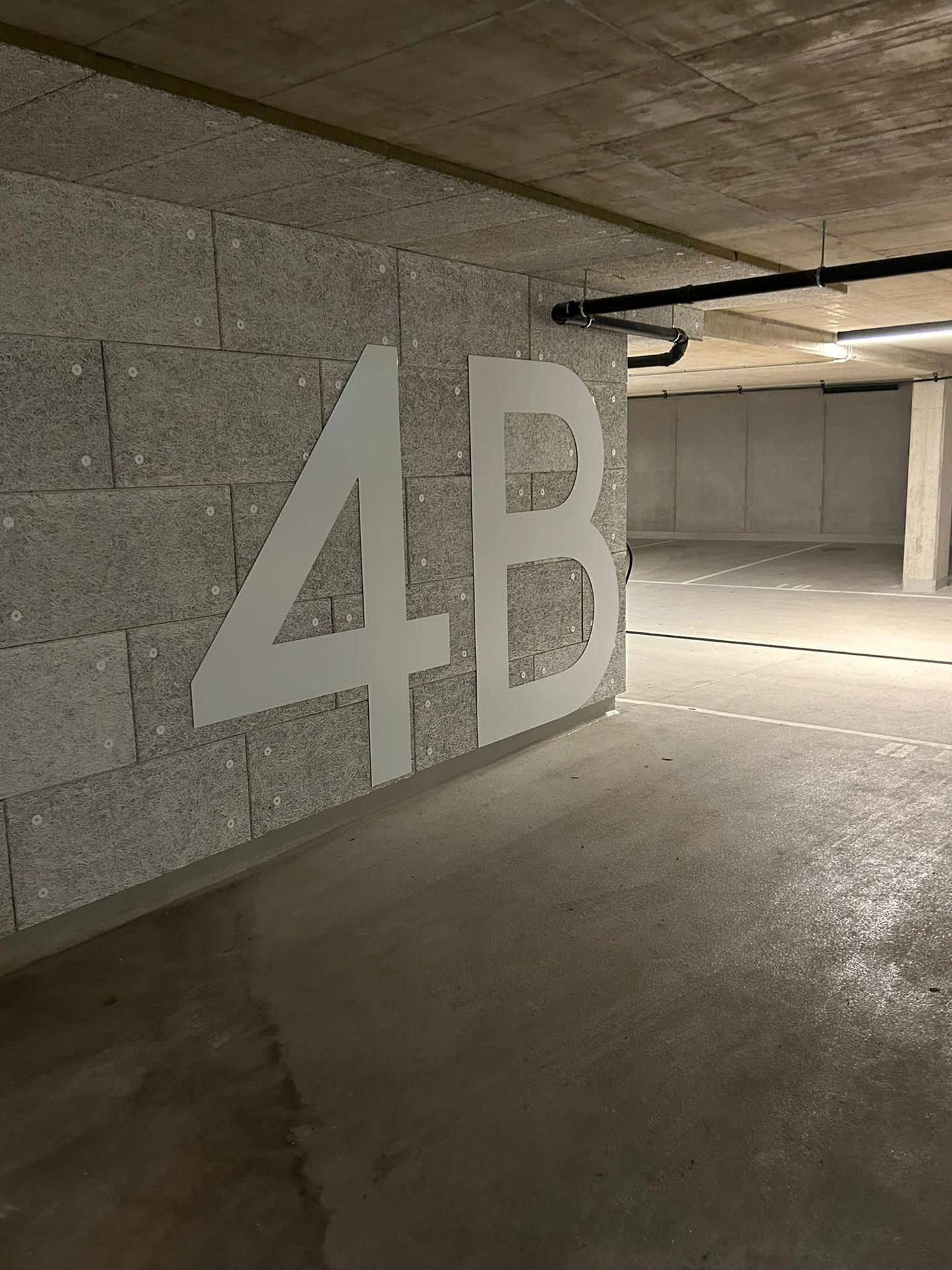 Geräumige Tiefgarage mit großer Beschriftung "4B" an einer strukturierten Wand und Betonboden.