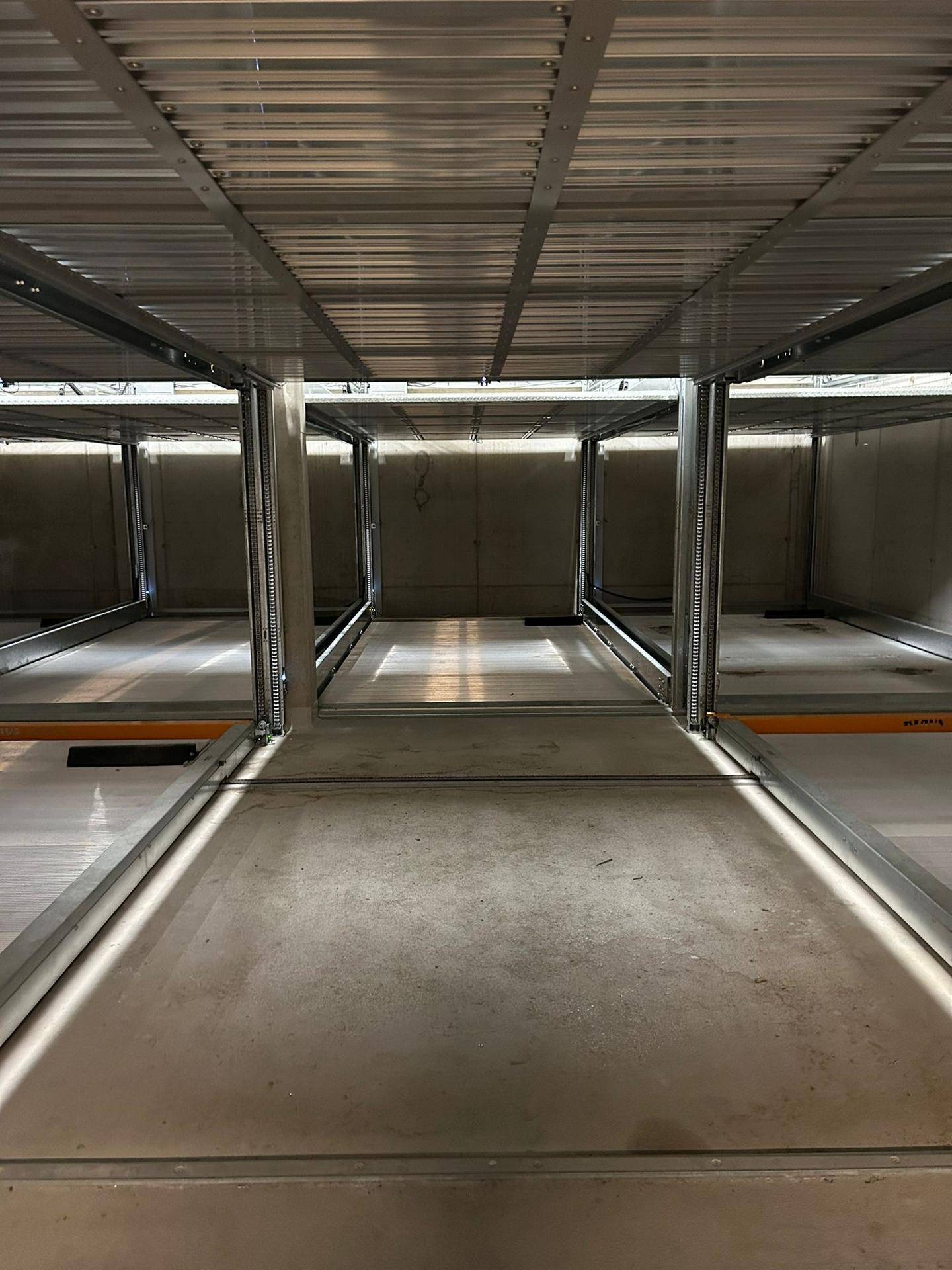 Innenansicht eines automatisierten Parksystems mit leeren Stellplattformen in einer modernen Tiefgarage.
