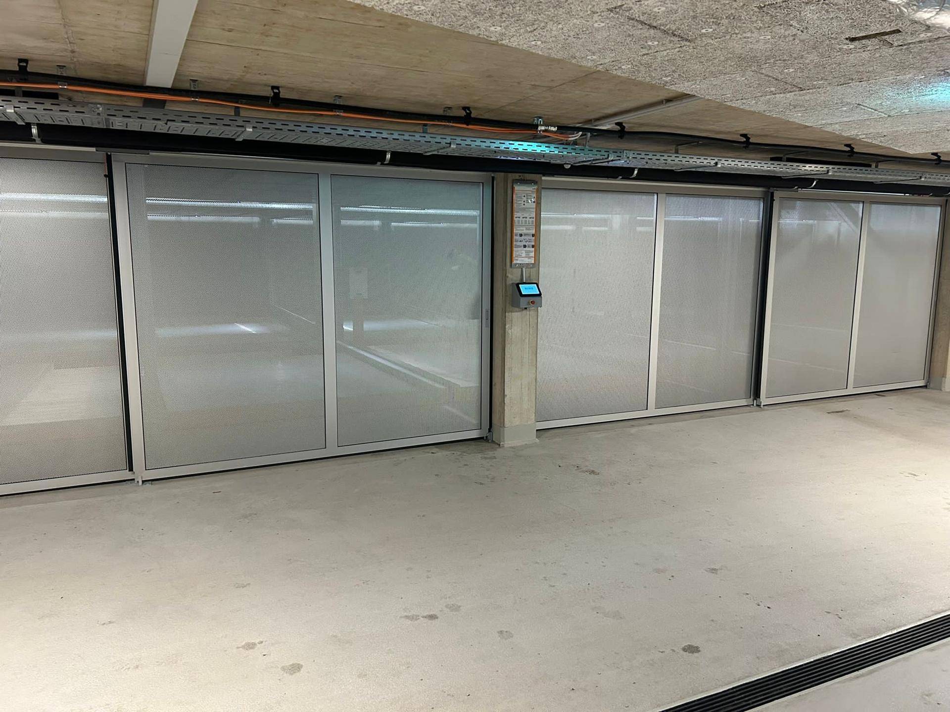 Geschlossene, automatisierte Parkbuchten in einer modernen Tiefgarage mit sauberem Betonboden und Metallverkleidungen.