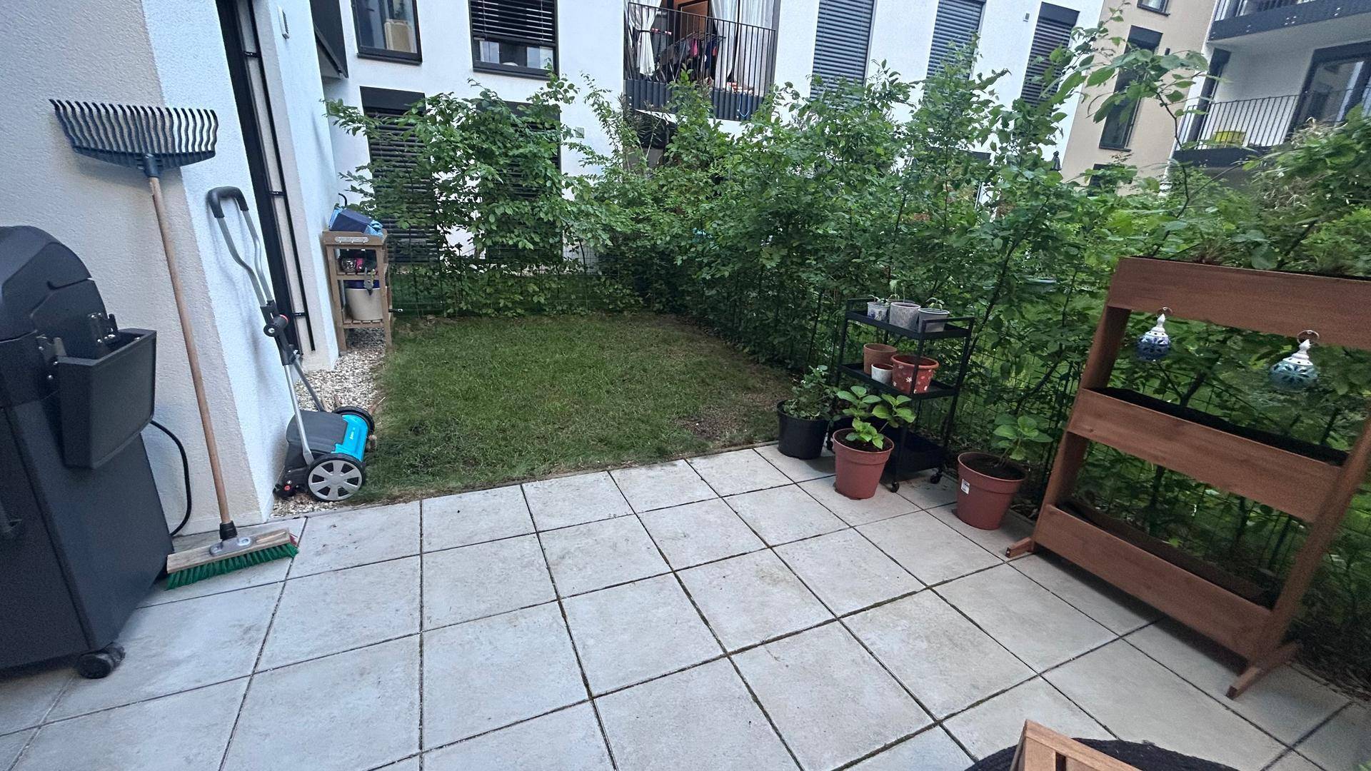 Kleiner privater Gartenbereich mit Rasenfläche, gepflasterter Terrasse und Hochbeet.