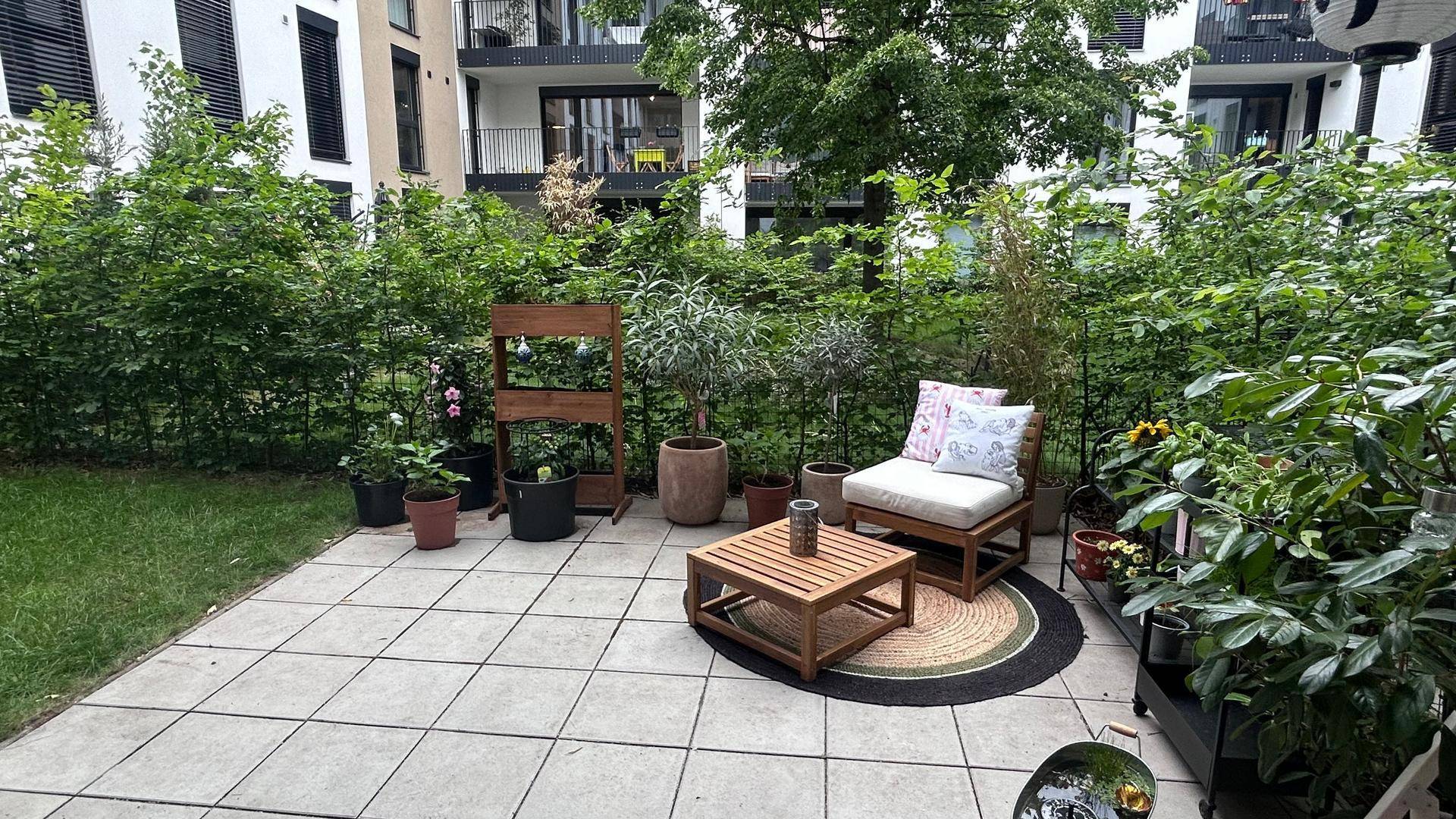 Gepflegter Gartenbereich mit Terrasse, Sitzgelegenheiten und üppiger Bepflanzung.