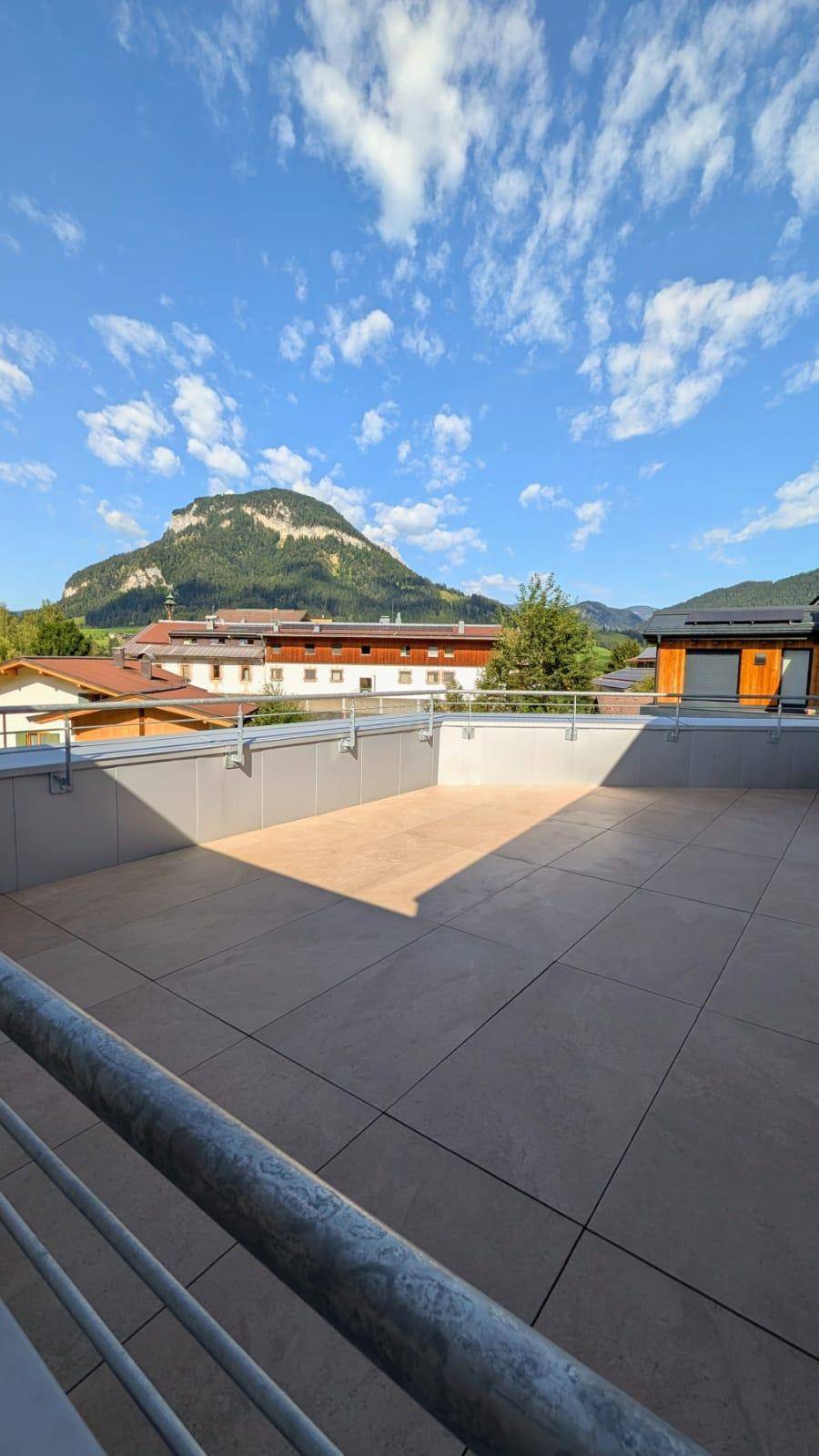 Geräumige Dachterrasse mit Fliesenboden und atemberaubendem Panoramablick auf die Berge und Umgebung.