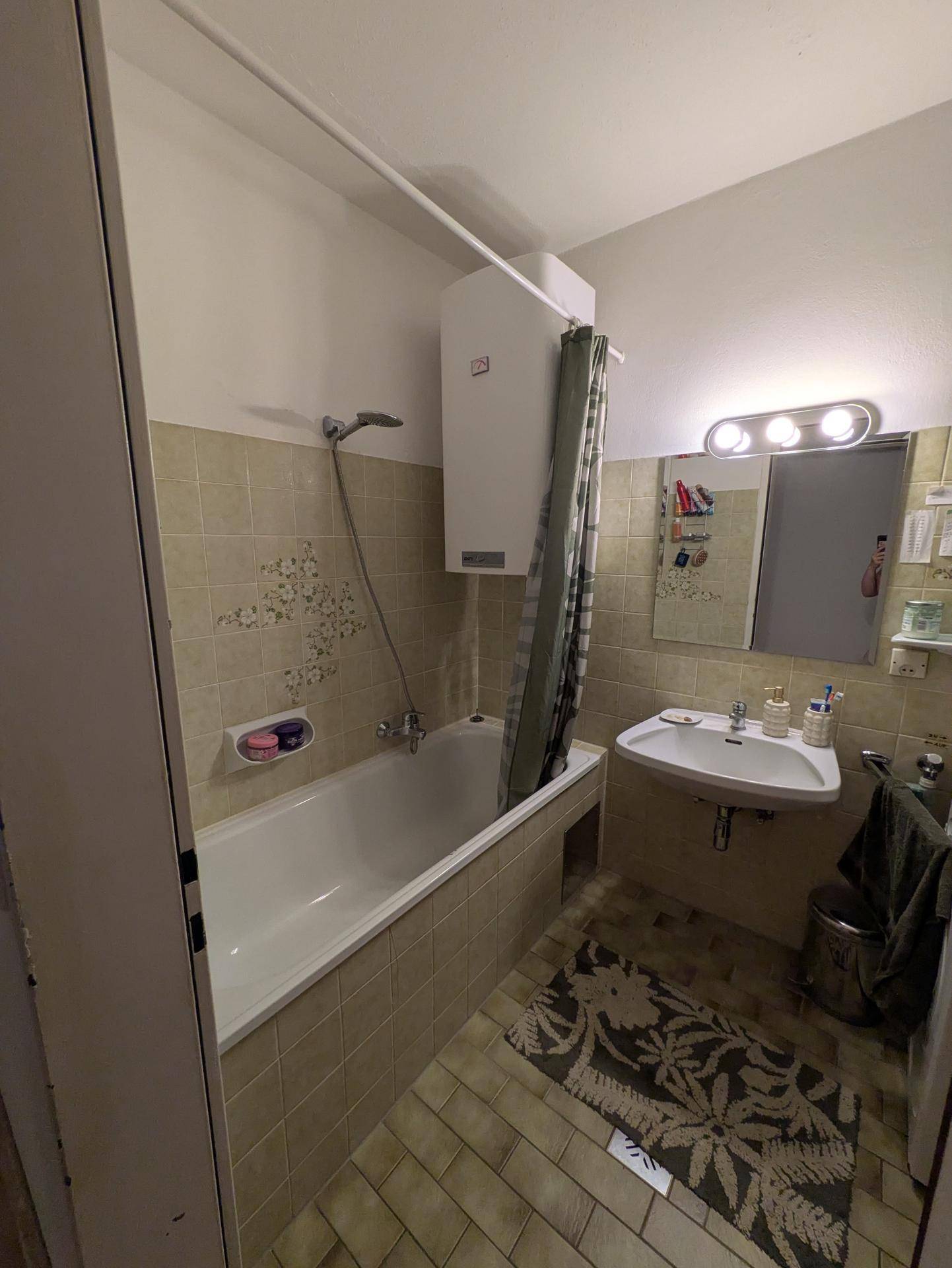 Badezimmer mit Badewanne, Waschbecken und Fliesen im Stil der 80er Jahre.