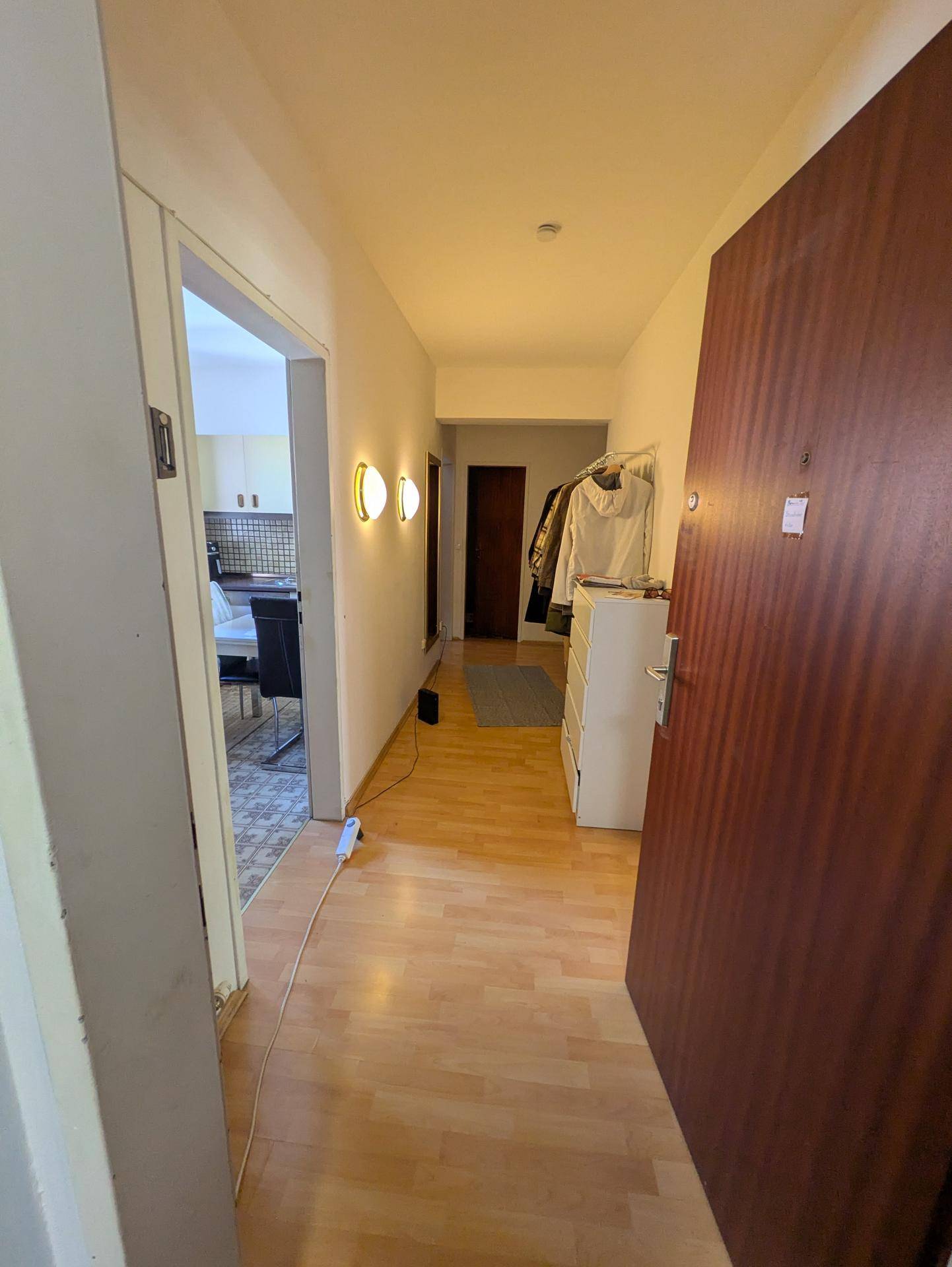 Heller Eingangsbereich mit Holzfußboden, Garderobe und Blick in die angrenzende Küche.