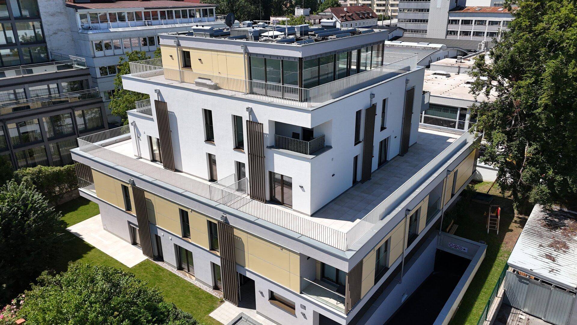 Gesamtansicht des modernen Wohngebäudes mit mehreren Terrassen und Grünflächen.