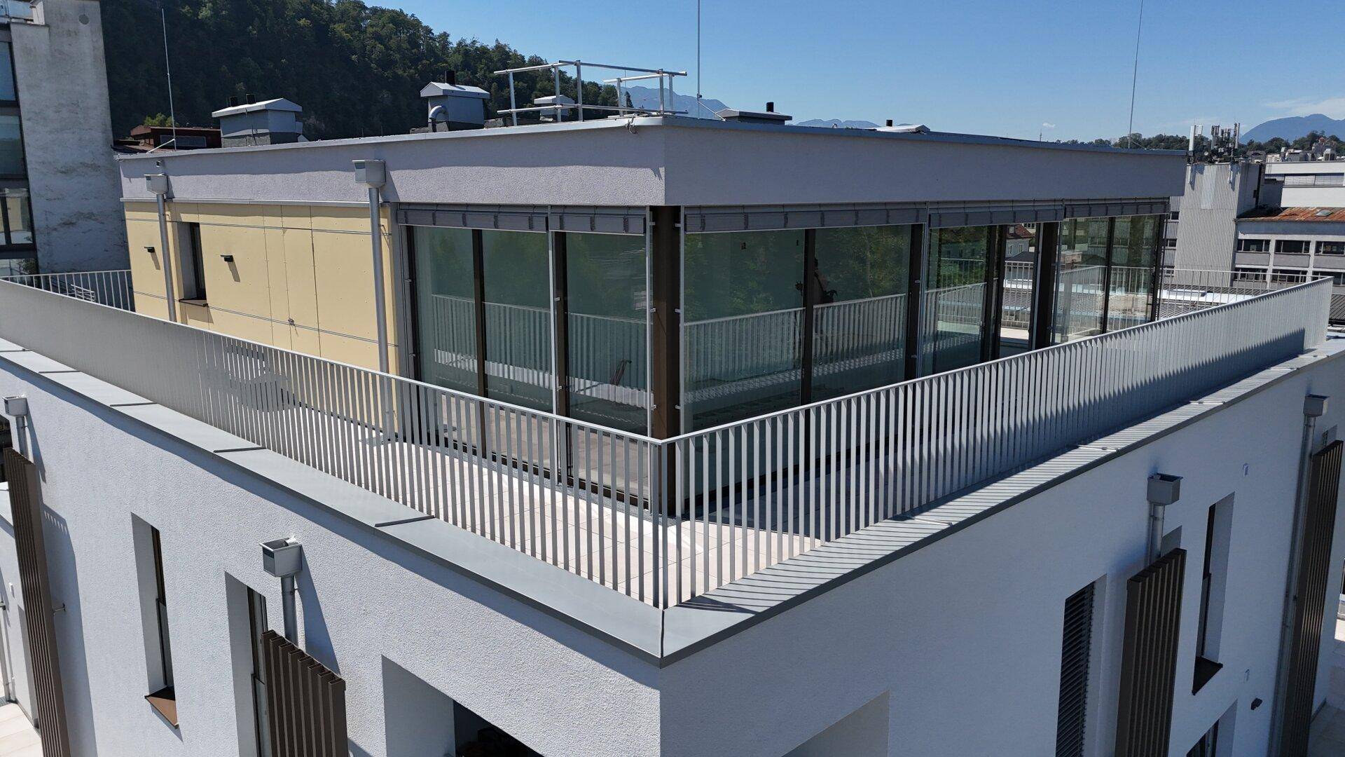 Draufsicht auf das moderne Gebäude mit Flachdach und umlaufenden Terrassenbereichen.